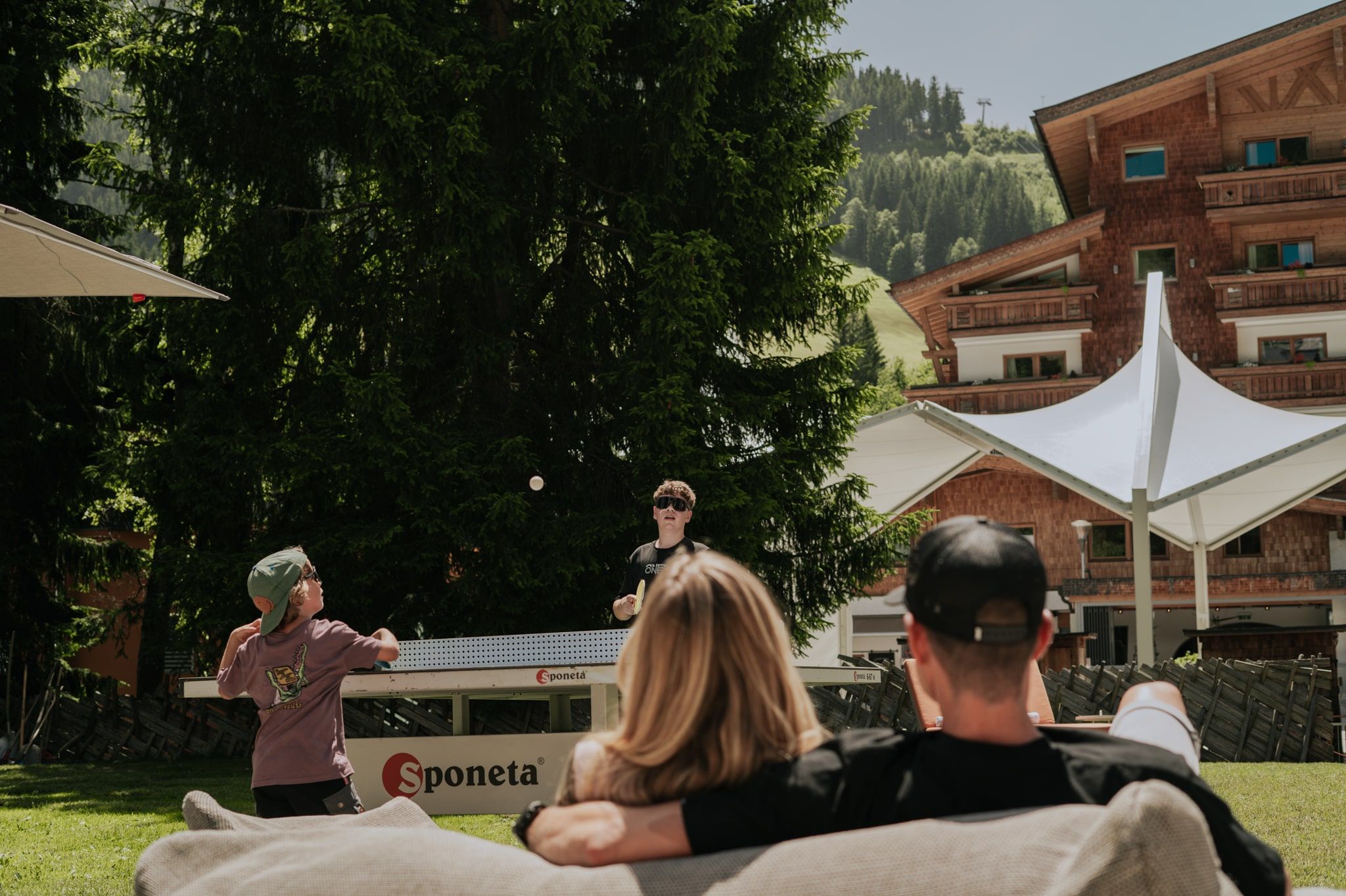 Boy plays table tennis in Glemmtal while others relax.