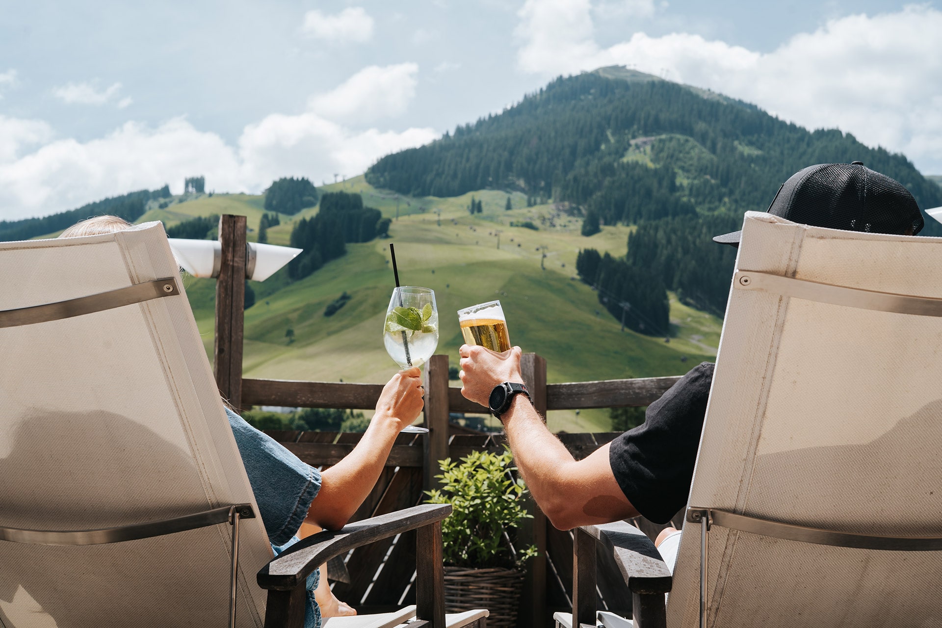 Entspannt sitzen zwei Personen auf der Terrasse des Glemmtalerhofs und genießen den Blick ins Glemmtal.
