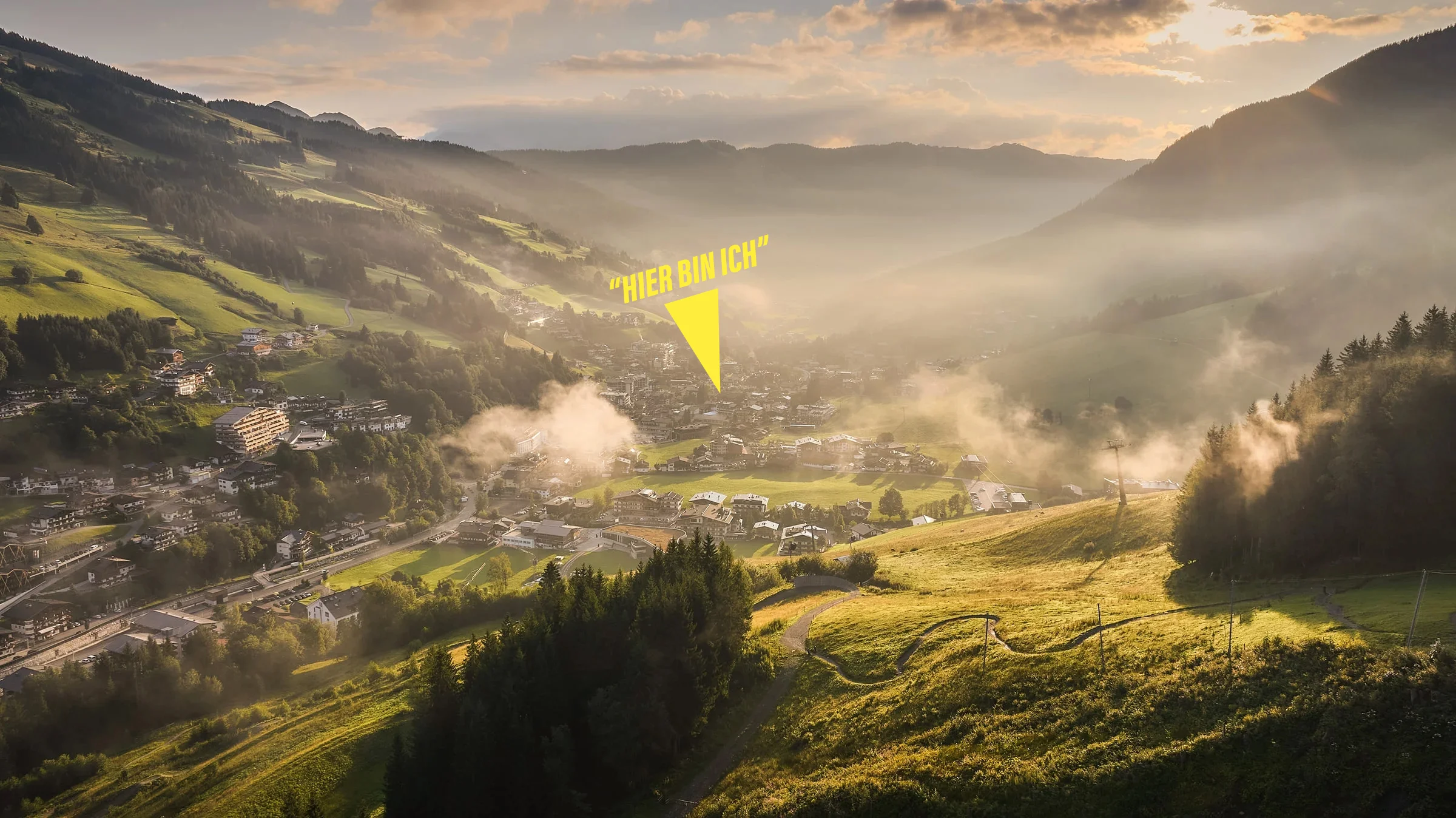 Eine Aussicht auf das Glemmtal mit sanften Hügeln und Nebel in der Morgensonne, ideal für Erholung und Natur.