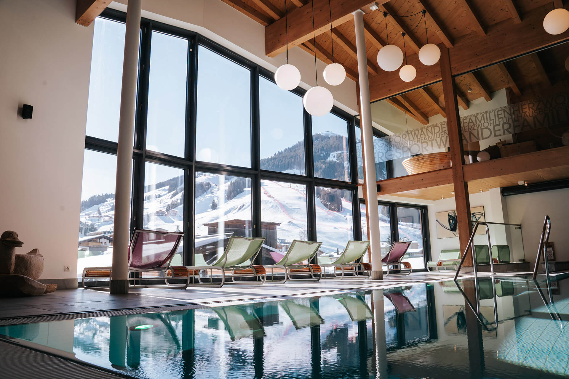 Das Glemmtalerhof in Hinterglemm bietet einen modernen Innenraum mit Pool und Blick auf die verschneiten Berge.