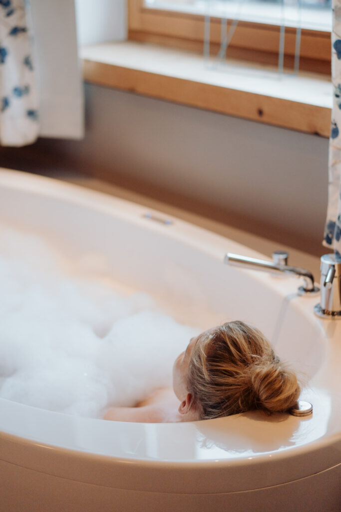 Eine Person entspannt in einer Badewanne mit Schaum, ideal nach einem Tag im Glemmtal oder im Glemmtalerhof.