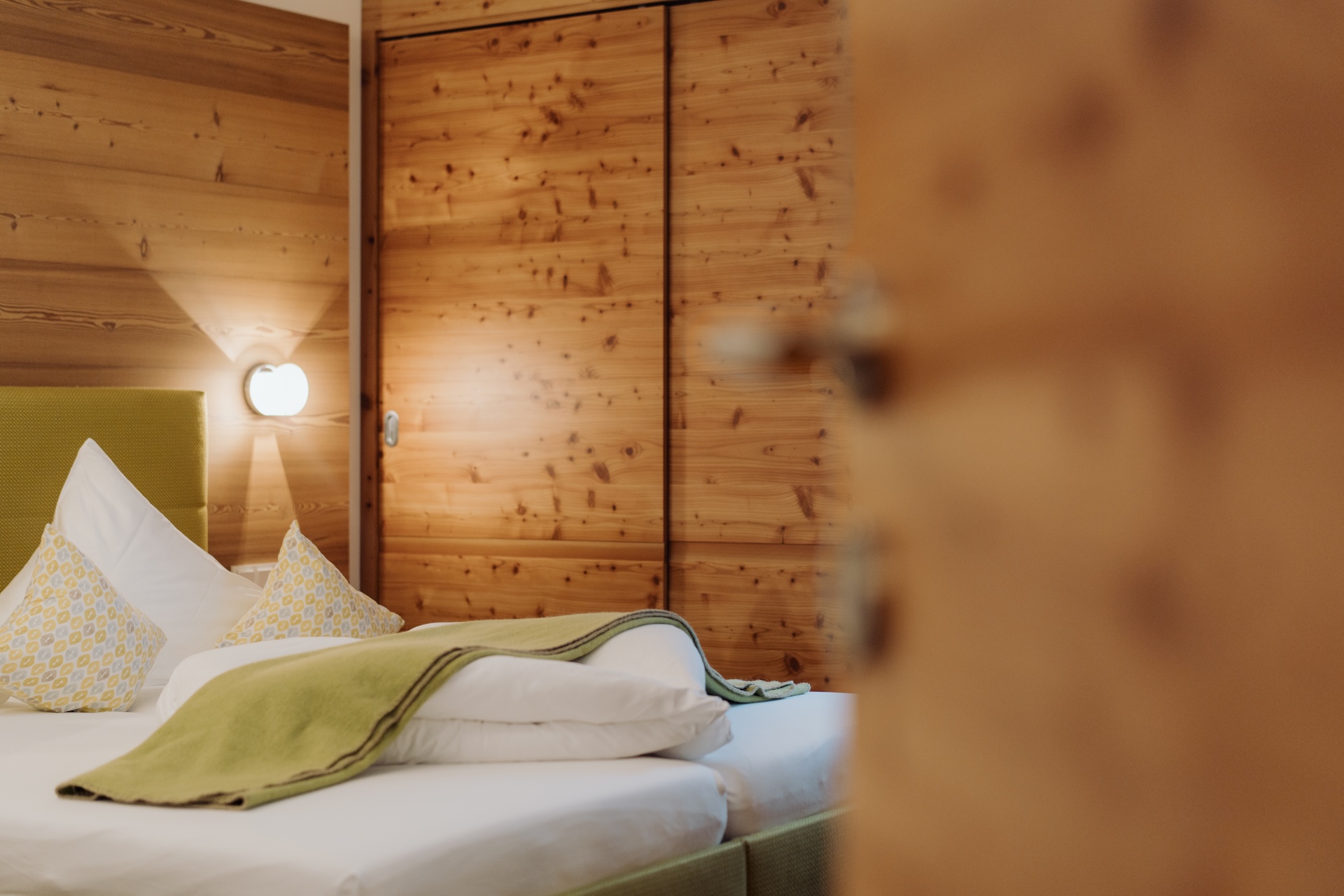 A cozy room at Glemmtalerhof in Hinterglemm, featuring wooden decor and a comfortable bed with decorative pillows.