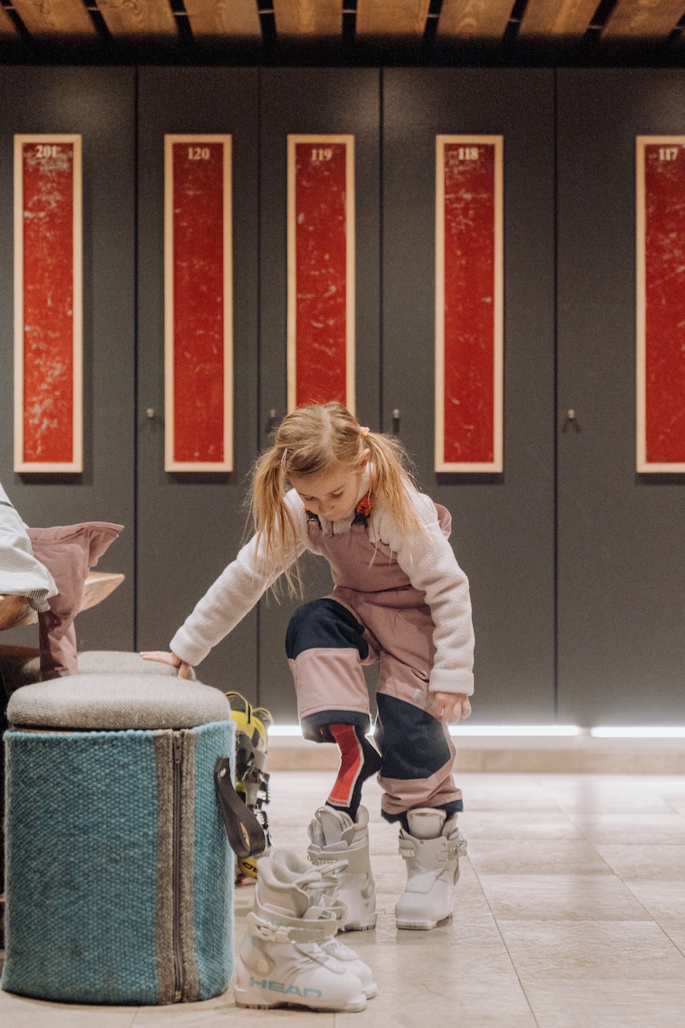 A girl prepares for skiing, adjusting her gear in a cozy setting, possibly in Glemmtal region.
