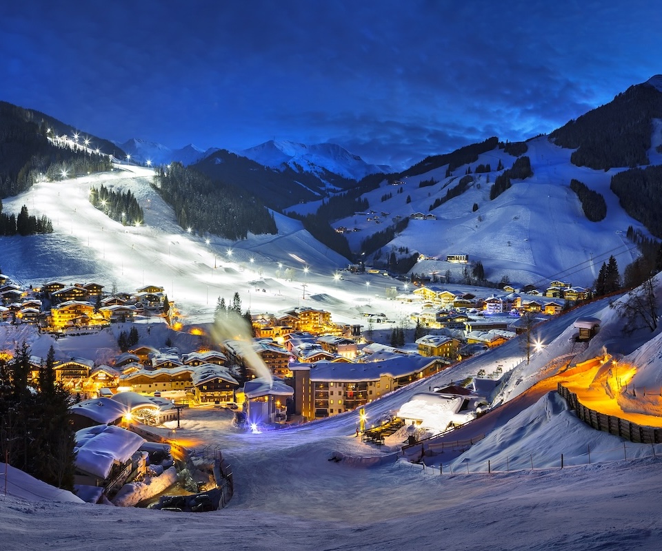 The snowy Glemmtal at dawn with twinkling lights and the Glemmtalerhof in Hinterglemm shining brightly.