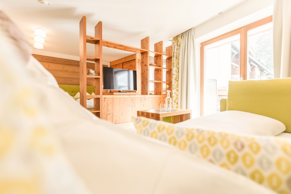 Gemütliches Zimmer im Glemmtalerhof in Hinterglemm, modern eingerichtet mit Holzelementen und Fenster für viel Licht.