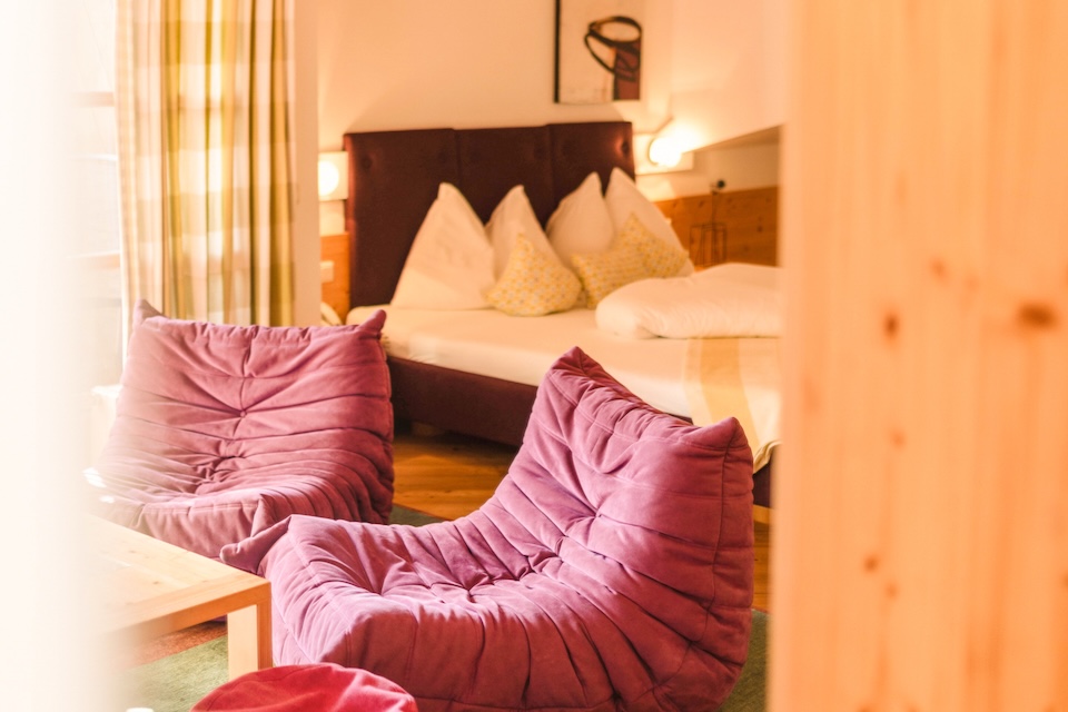 Stilvolles Zimmer im Glemmtalerhof in Hinterglemm mit gemütlichen Sesseln und einem einladenden Bett.