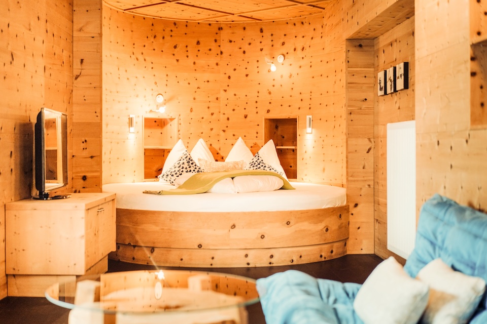 Modernes Zimmer im Glemmtalerhof in Hinterglemm, mit Holzdesign und runder Bettanlage. Gemütliche Atmosphäre.