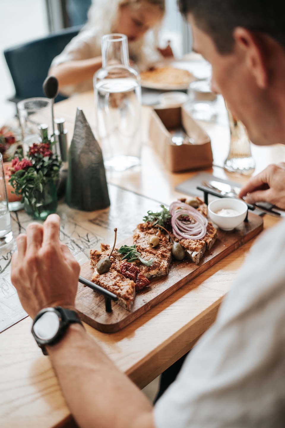 A man enjoys a meal at Glemmtalerhof in Hinterglemm with a child in the background and a beautifully arranged dish.
