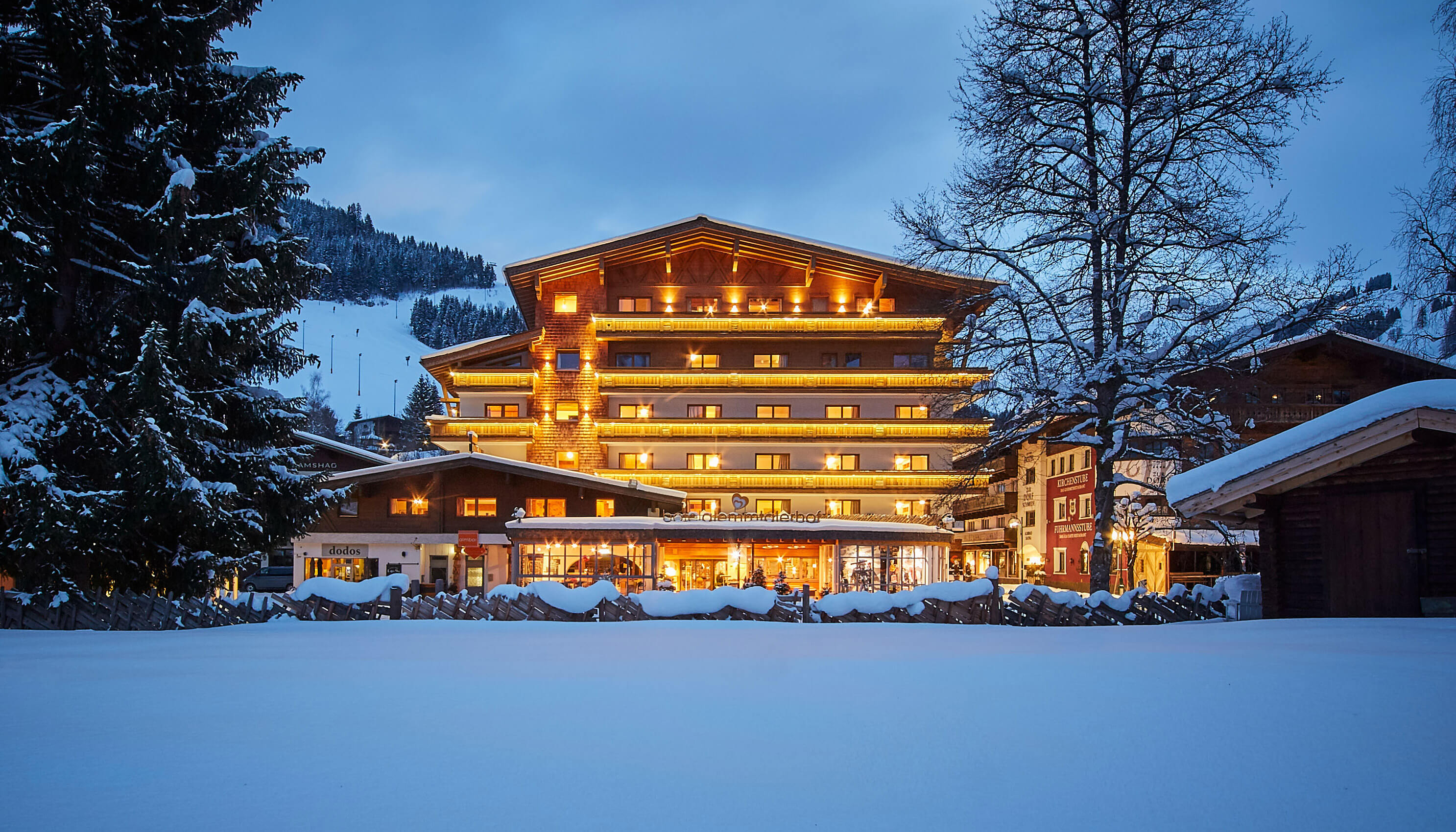 The Glemmtalerhof in Hinterglemm stands beautifully lit against a snowy landscape, showcasing a cozy alpine retreat.