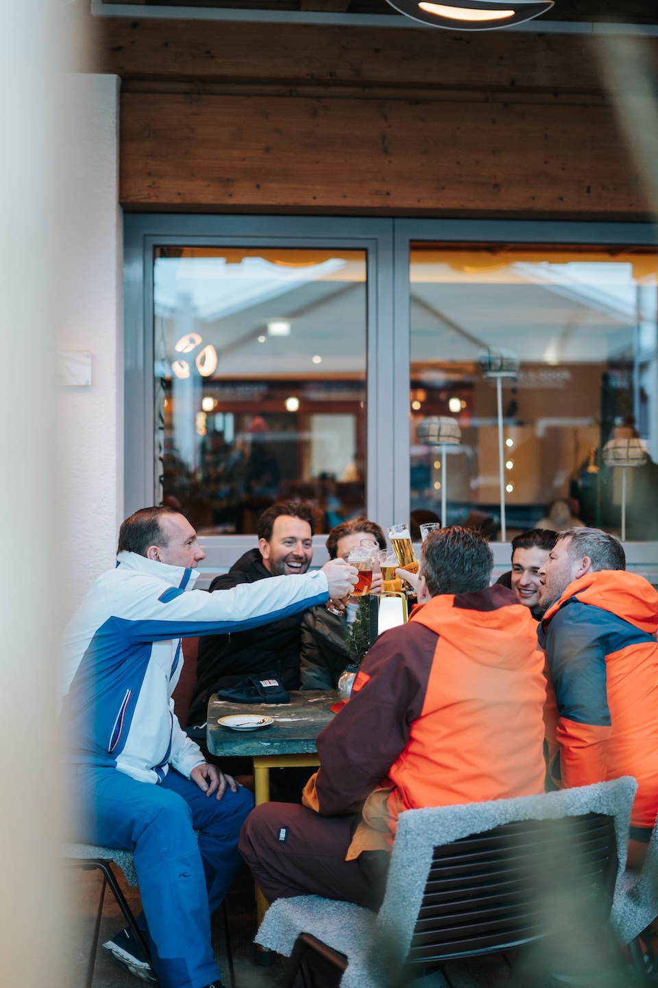 A group of friends toasting with beers at a cozy table in Glemmtalerhof in Hinterglemm enjoying the atmosphere.