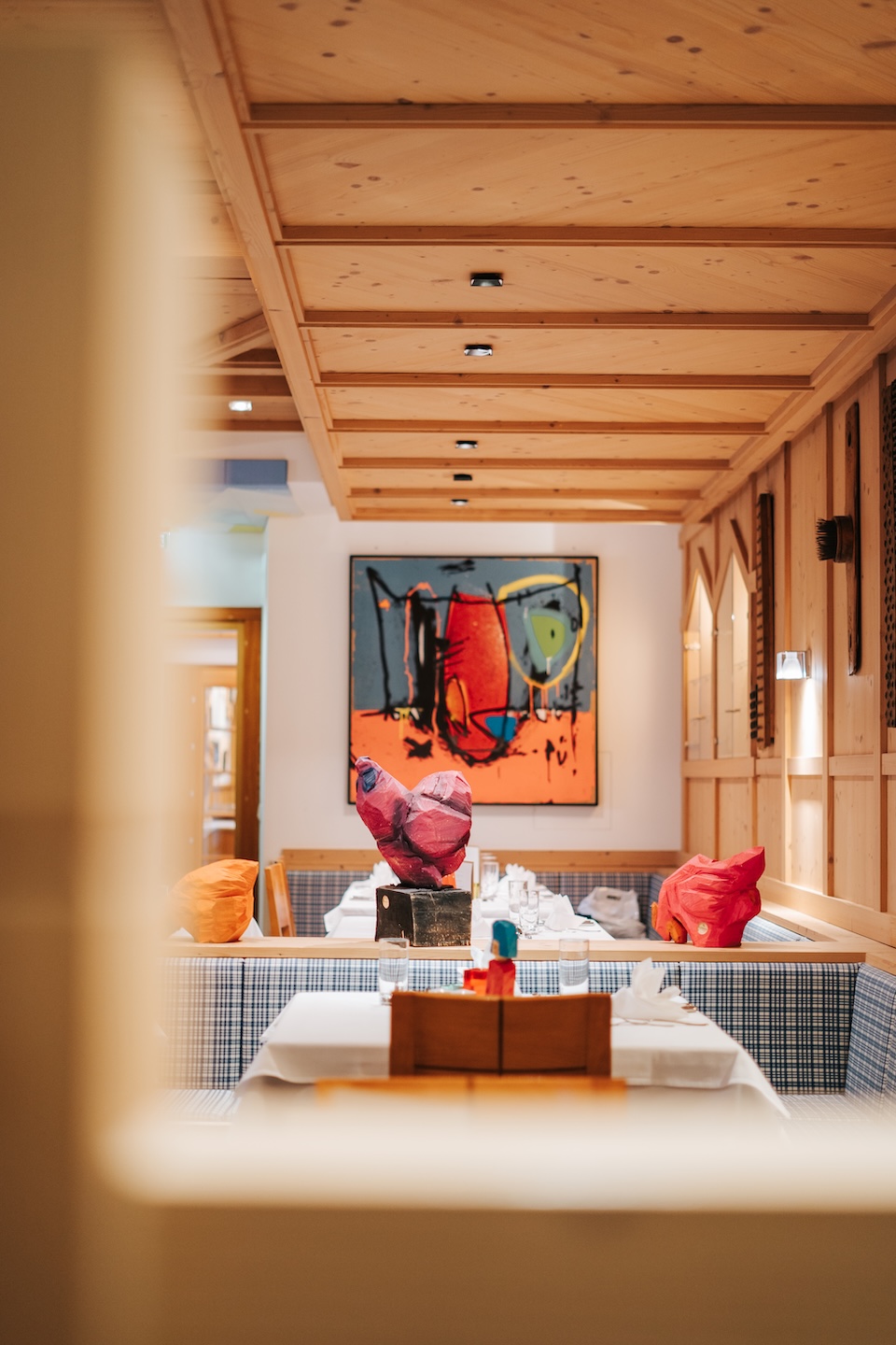 A cozy interior of Glemmtalerhof features colorful art and decor with tables set for dining in Hinterglemm.