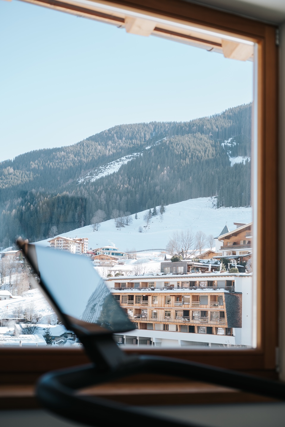 A view from a window showcases snowy mountains and buildings in the Glemmtal area, near Hinterglemm.