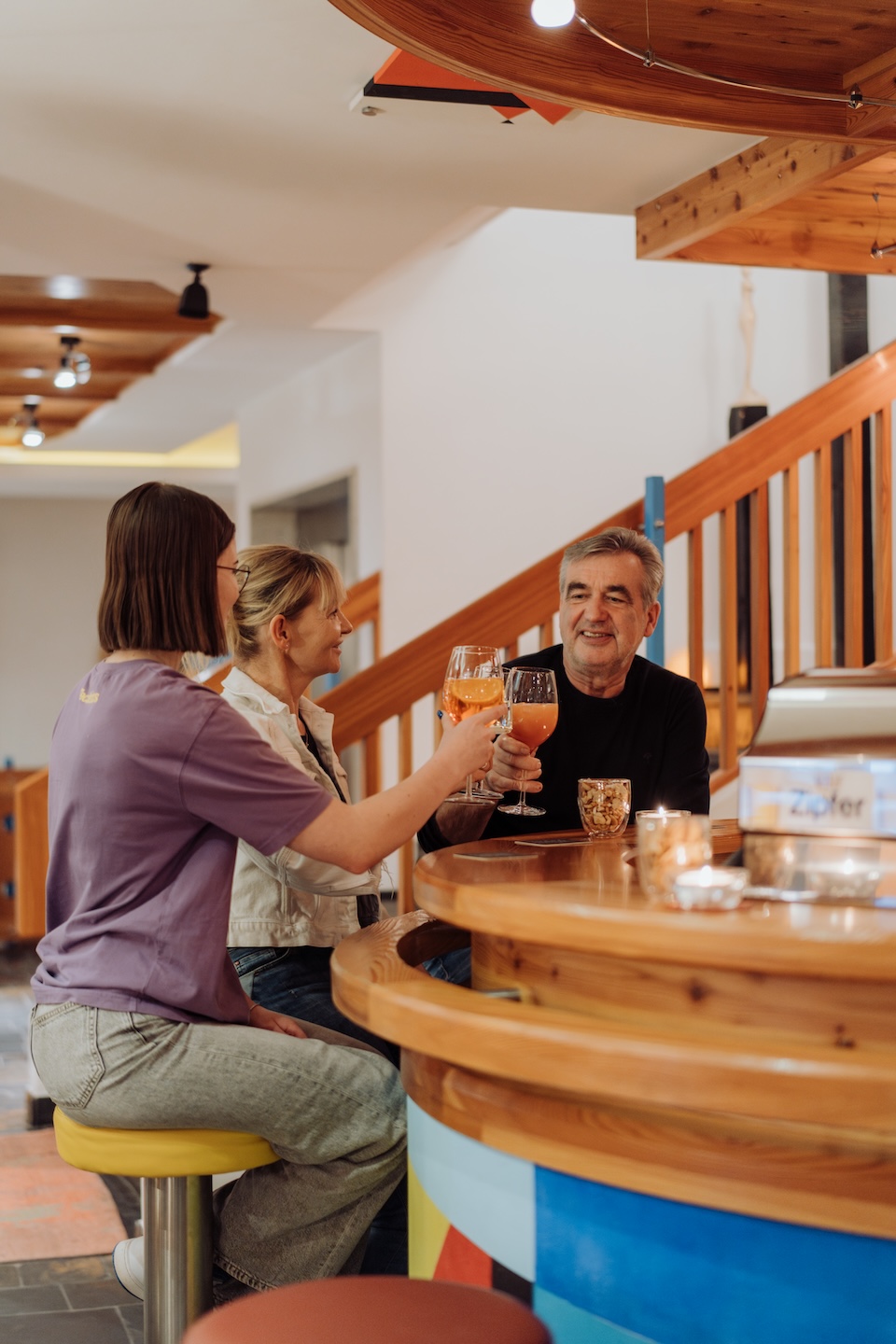 Freunde stoßen in der Bar des Glemmtalerhof in Hinterglemm an, gemütliche Atmosphäre und fröhliche Stimmung.