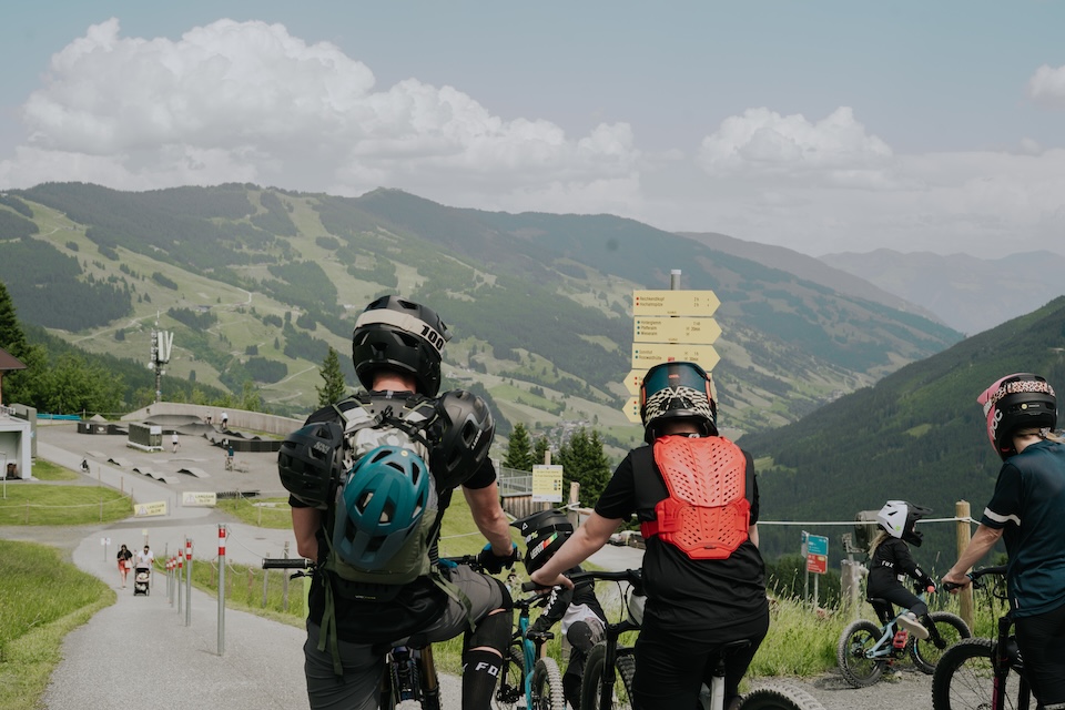 Radfahrer blicken ins Glemmtal, bereit für ein Abenteuer in Hinterglemm. Die Landschaft ist beeindruckend und grün.
