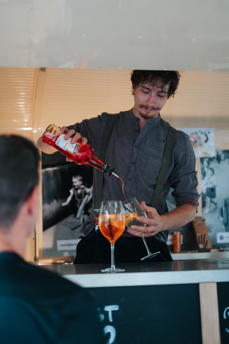 Ein Barkeeper schuetet Getränke an einer Bar im Glemmtal, Hinterglemm. Gemütliche Atmosphäre und frische Cocktails.