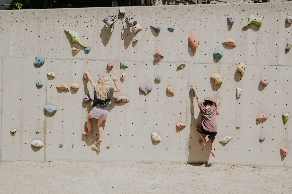 Kinder klettern aktiv an einer bunten Kletterwand im Glemmtal in Hinterglemm. Spaß und Bewegung in der Natur!