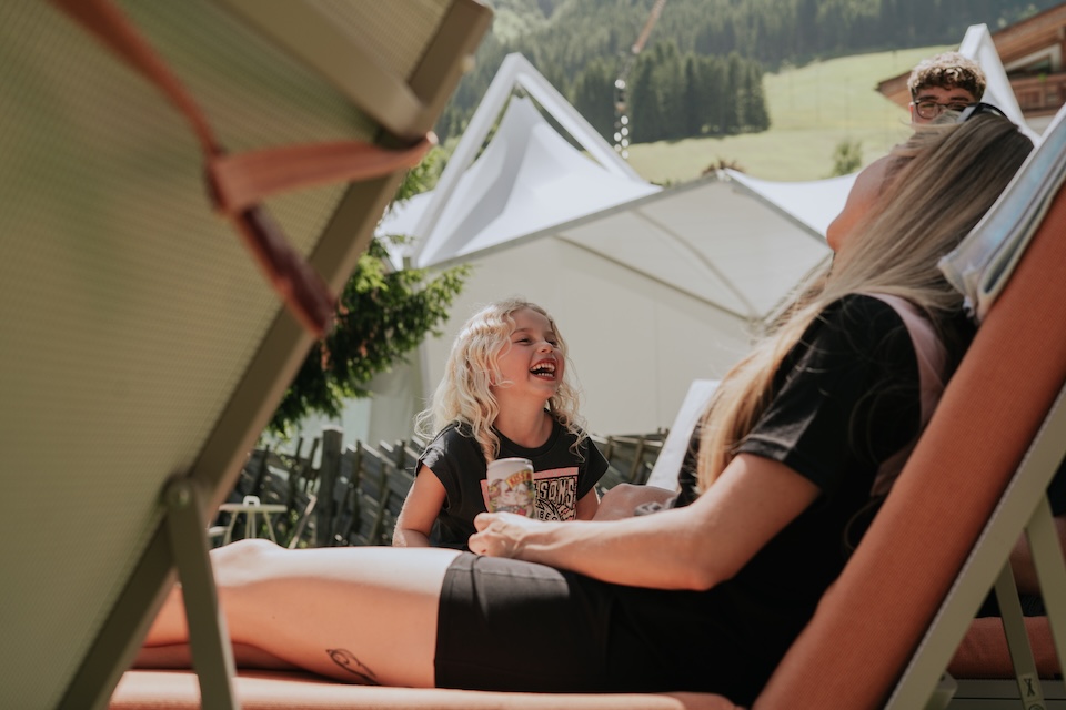 Im Glemmtal lachen Kinder und entspannen Erwachsene in Liegestühlen an einem sonnigen Tag.
