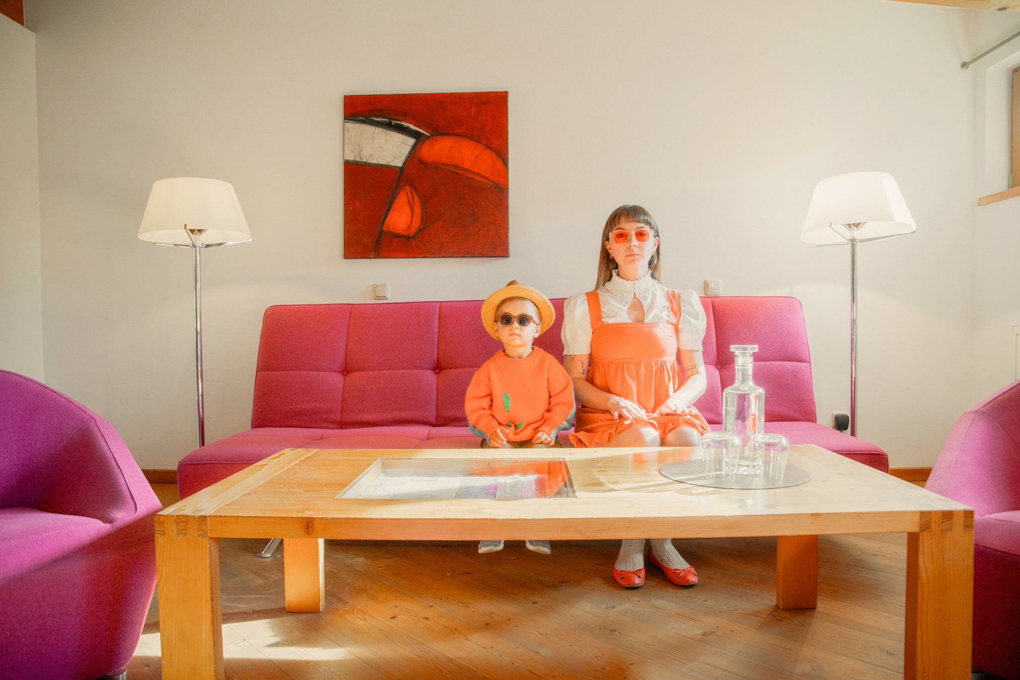 Ein Junge und eine Frau in orangefarbenen Outfits sitzen in einem modernen Raum im Glemmtal.