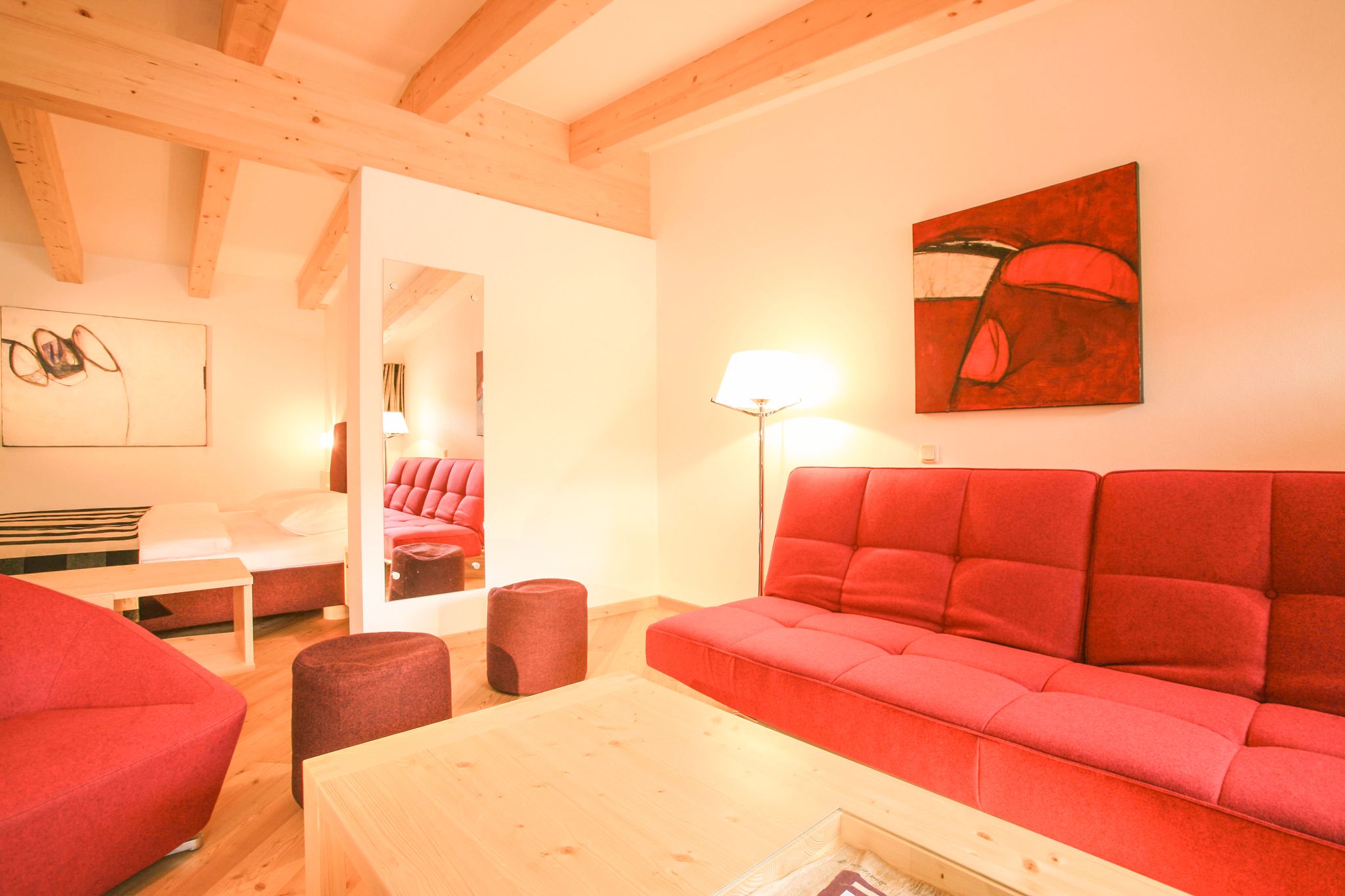 A modern room in Glemmtalerhof in Hinterglemm with a red sofa and wooden ceiling.