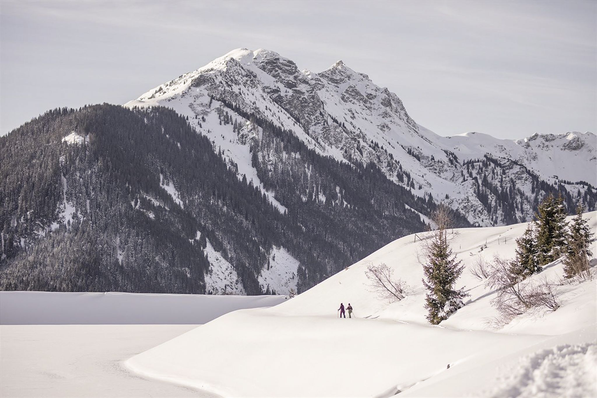 Winter landscape in Glemmtal with hikers and snowy mountains.