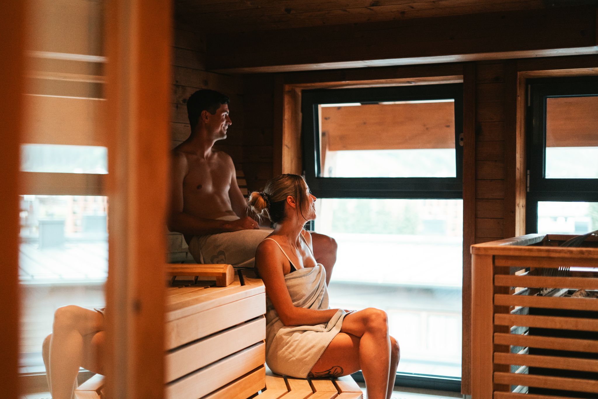 Two people relax in the sauna at Glemmtalerhof in Hinterglemm, enjoying the mountain view.