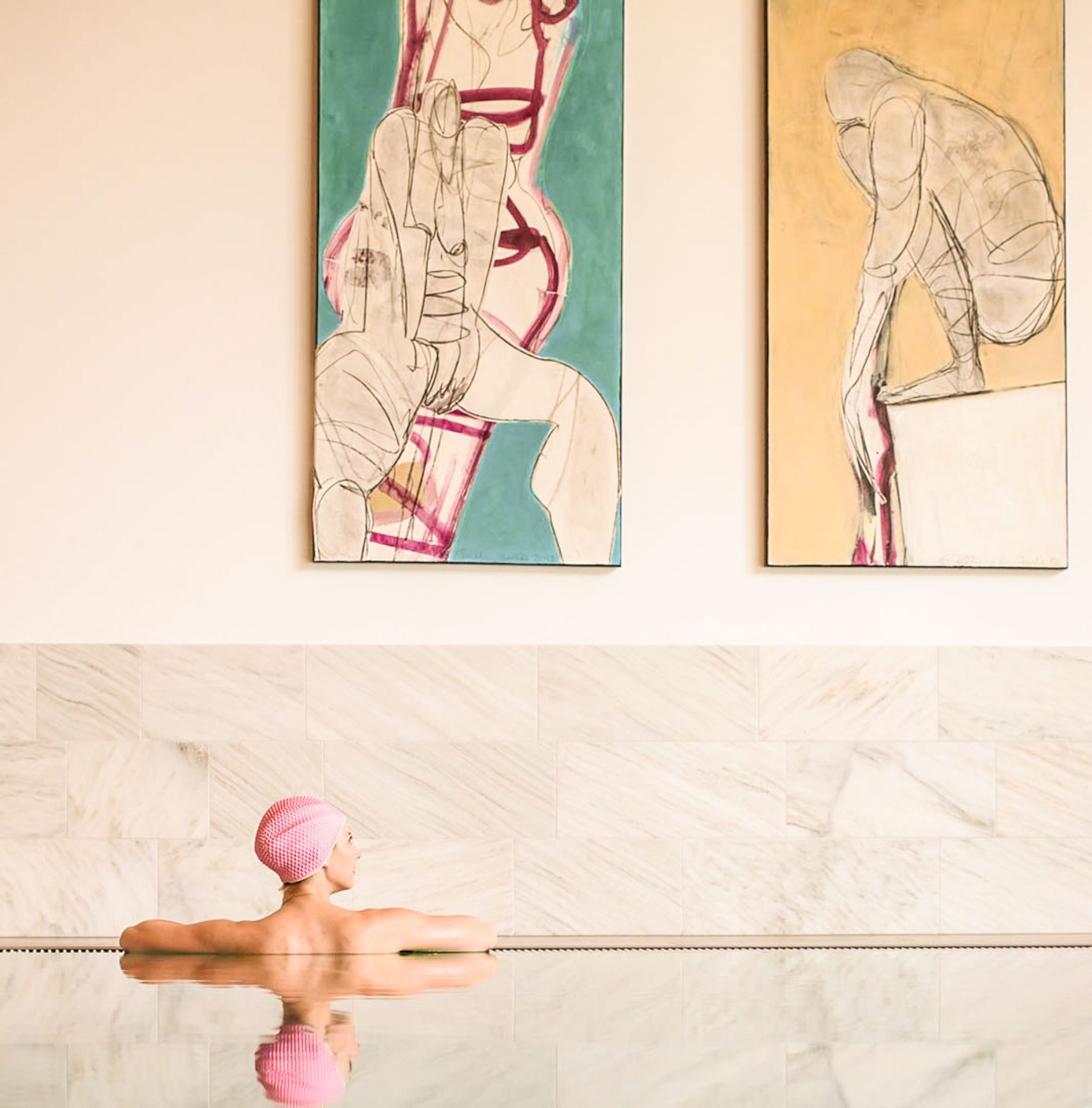 A person relaxes in water at Glemmtalerhof, with artworks on the wall in the background.