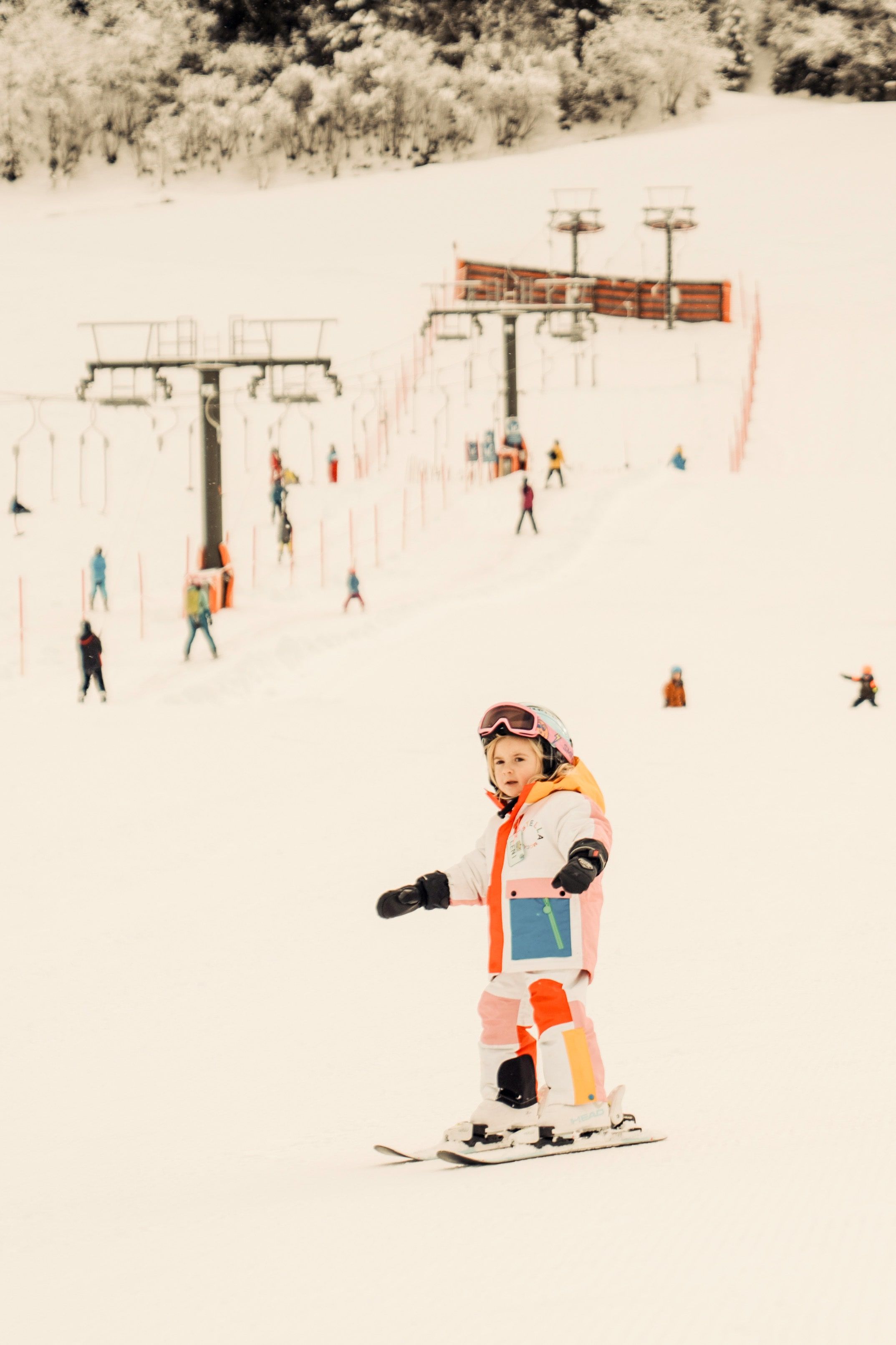 Ein kleines Mädchen fährt Ski im Glemmtal bei Hinterglemm, umgeben von vielen anderen Skifahrern.