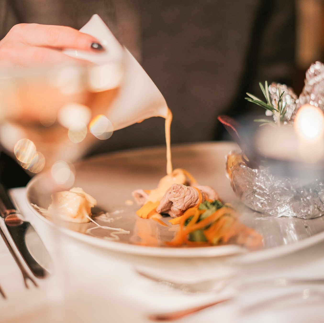 A hand pours sauce onto a plate at Glemmtalerhof in Hinterglemm.