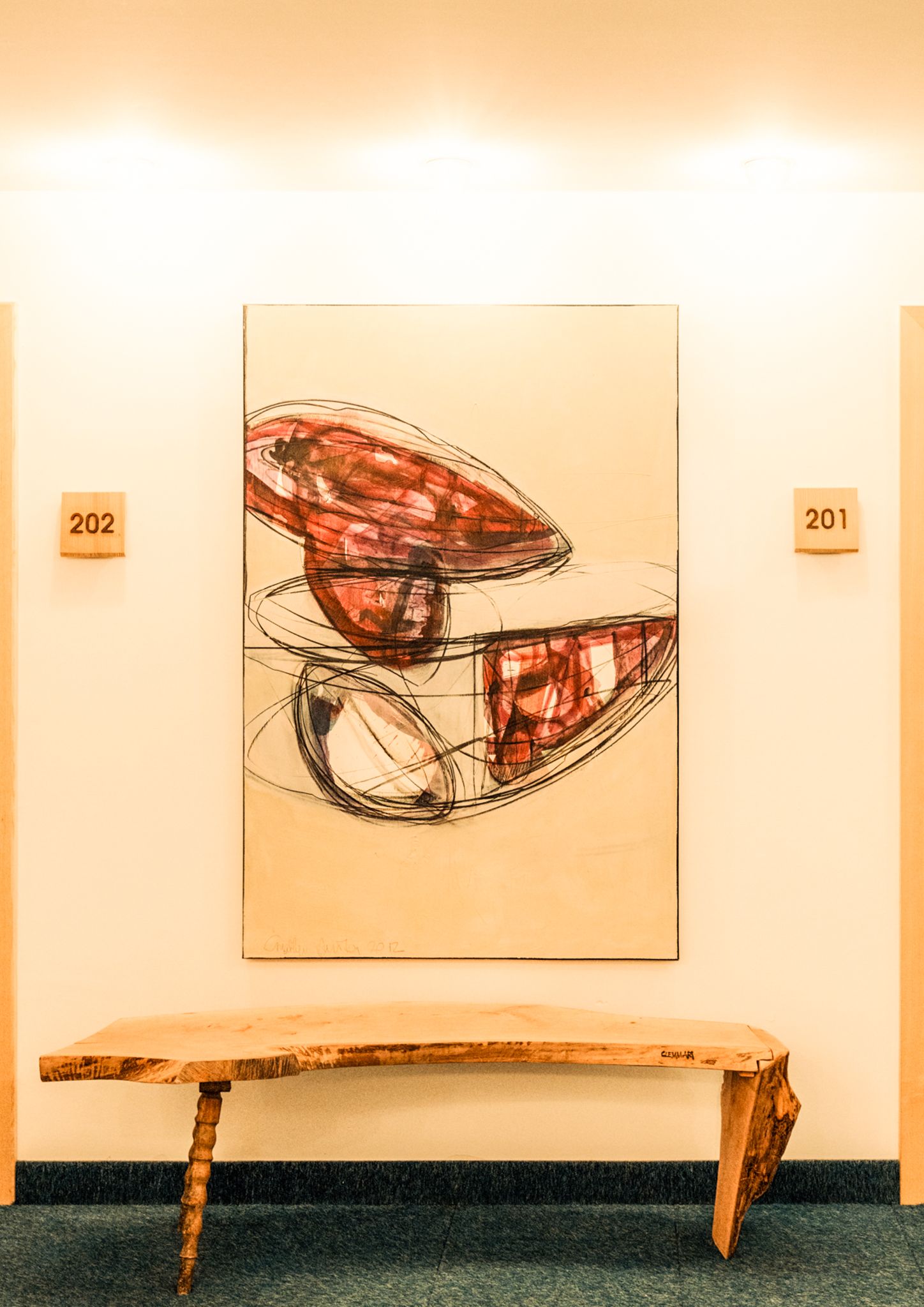 Glemmtalerhof in Hinterglemm mit moderner Kunst und einer Holzbank im Flur.