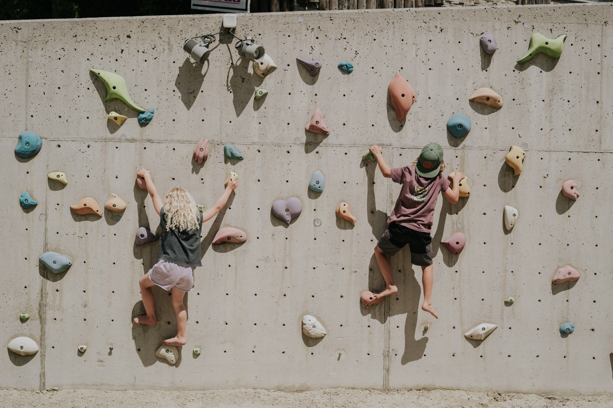 Kinder klettern an einer bunten Kletterwand im Glemmtal