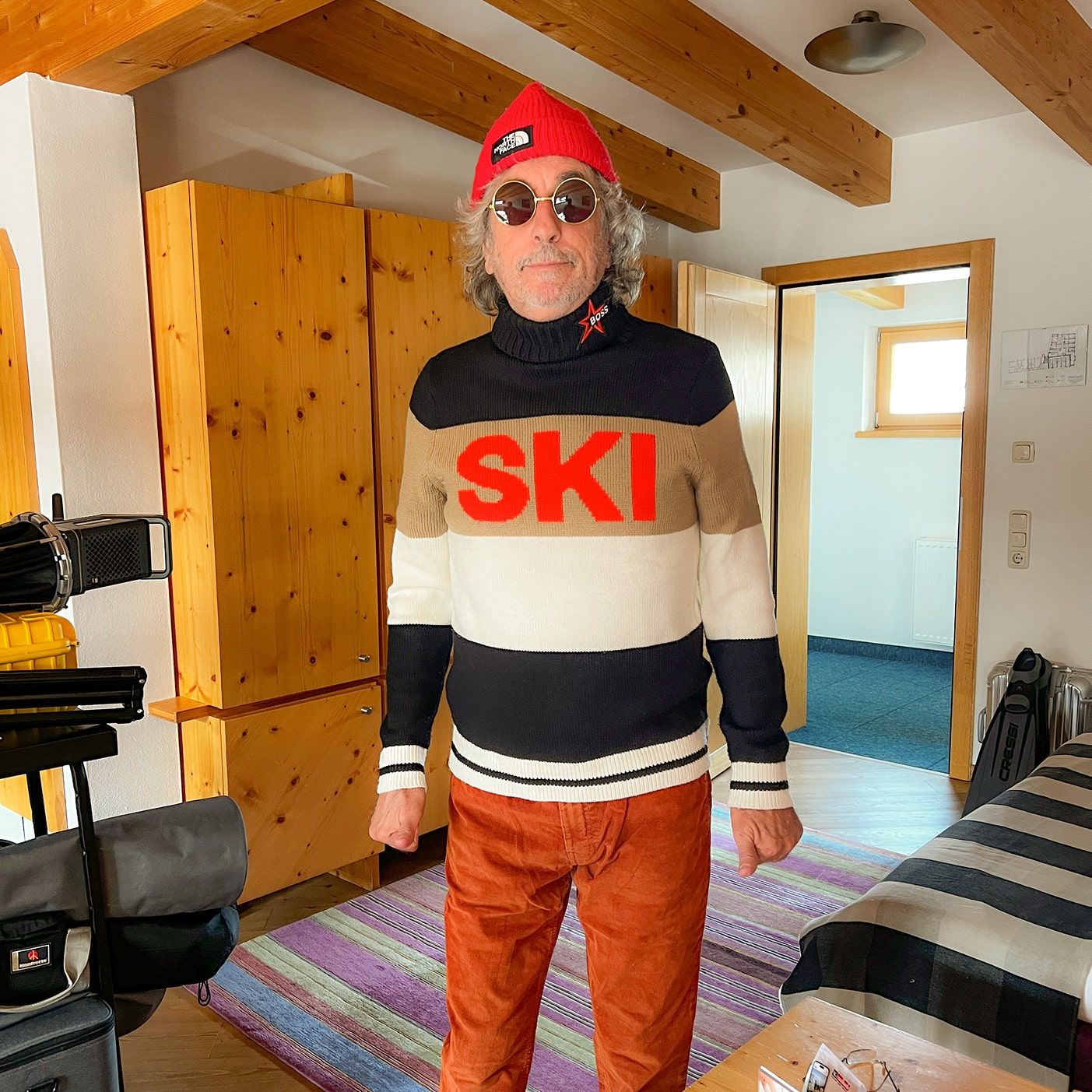 A man in a ski sweater stands in a cozy room in Glemmtal.