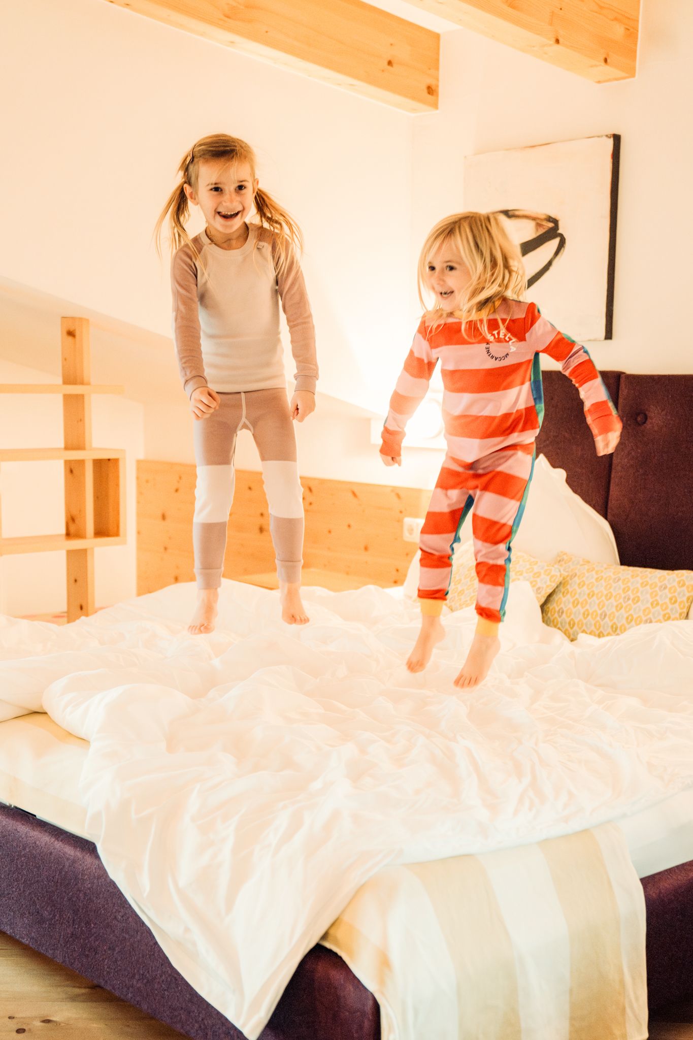 Two kids joyfully jump on a bed at Glemmtalerhof in Hinterglemm.