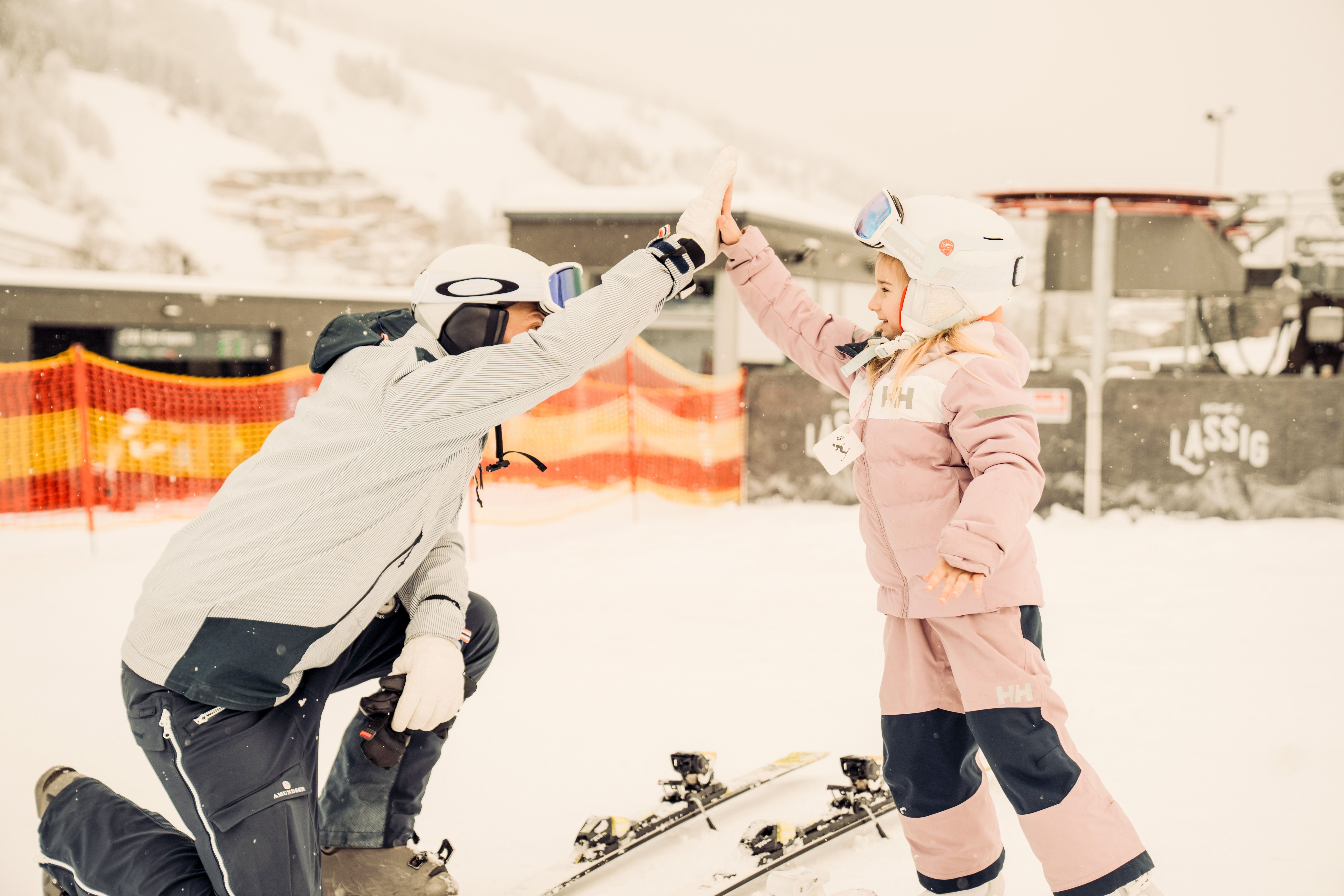 A ski instructor gives a high five to a child in the snowy Glemmtal. Enjoying