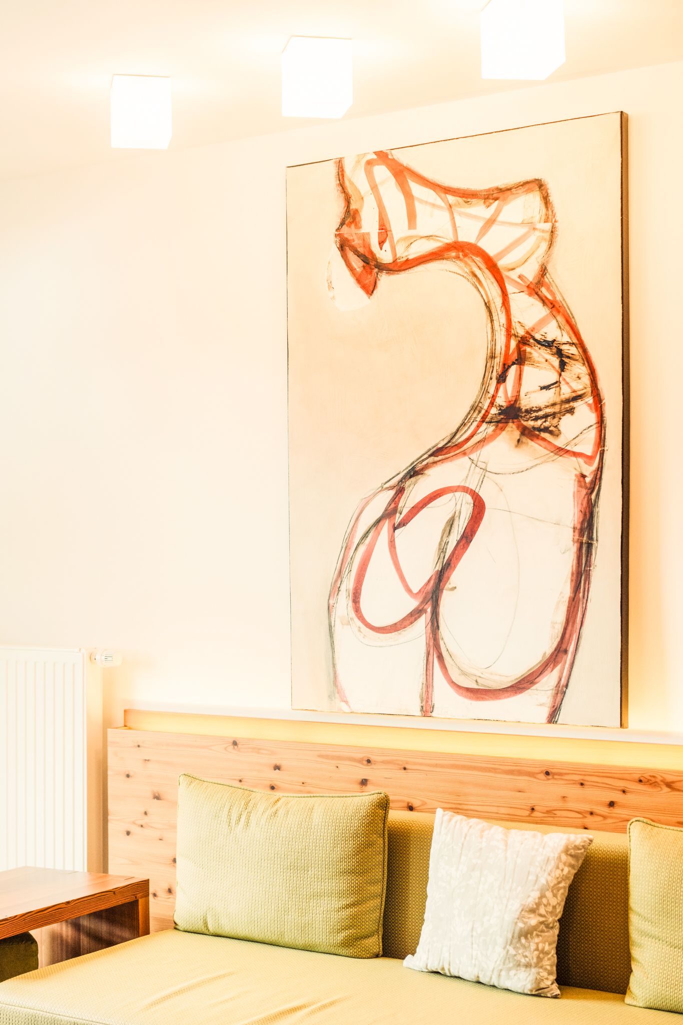 Ein helles Zimmer im Glemmtalerhof mit einem modernen Kunstwerk über einem gemütlichen Sofa.