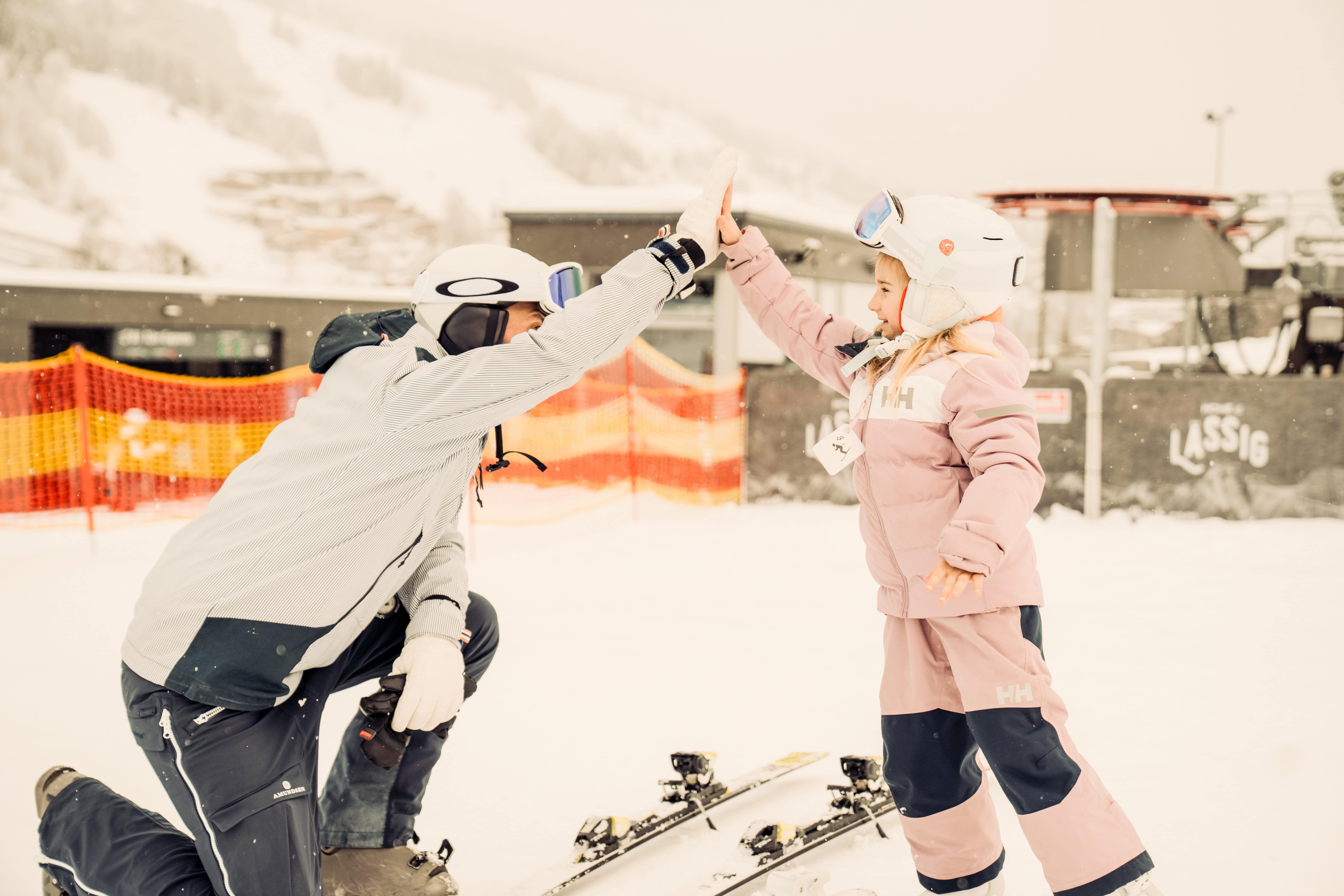 Ein Erwachsener und ein Kind teilen einen fröhlichen Moment im Schnee am Glemmtalerhof in Hinterglemm.