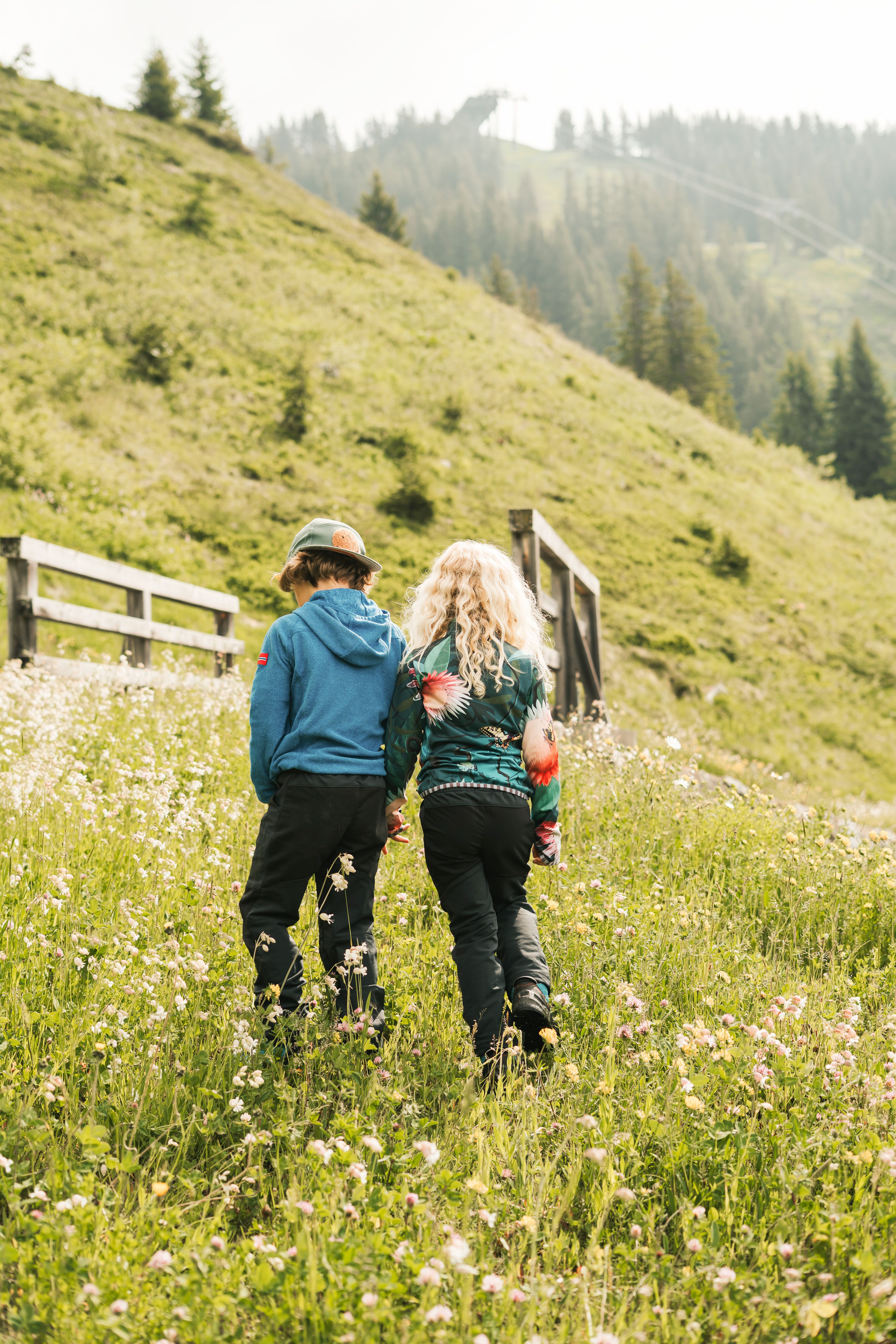 Children walk in Glemmtal over a flowering meadow.