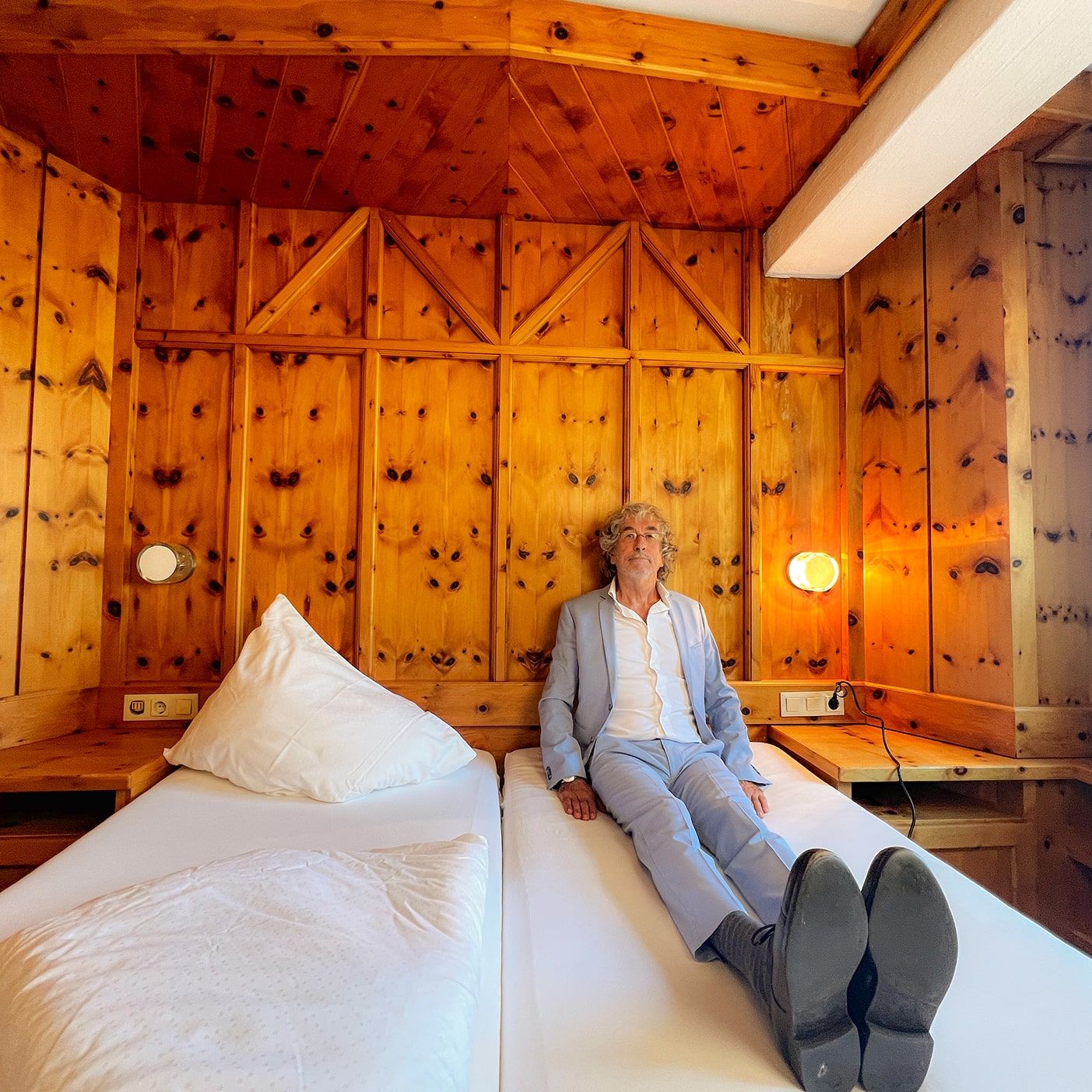 A man relaxes on a bed in a cozy room at Glemmtalerhof.