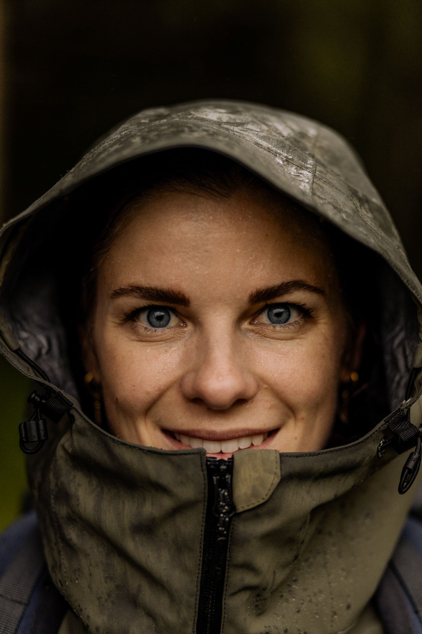 A woman in a raincoat smiles. The background is nature in Glemmtal.