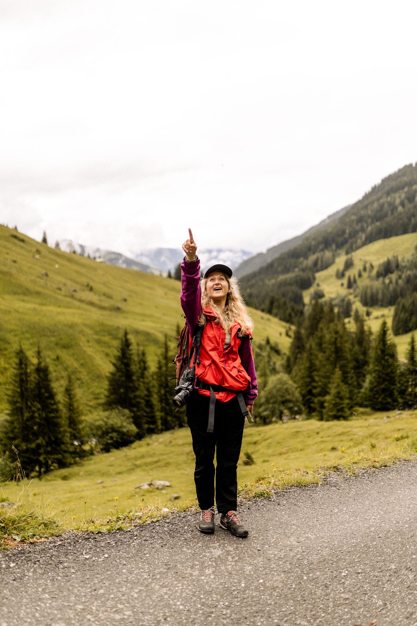 A woman points upwards in the Glemmtal while hiking.