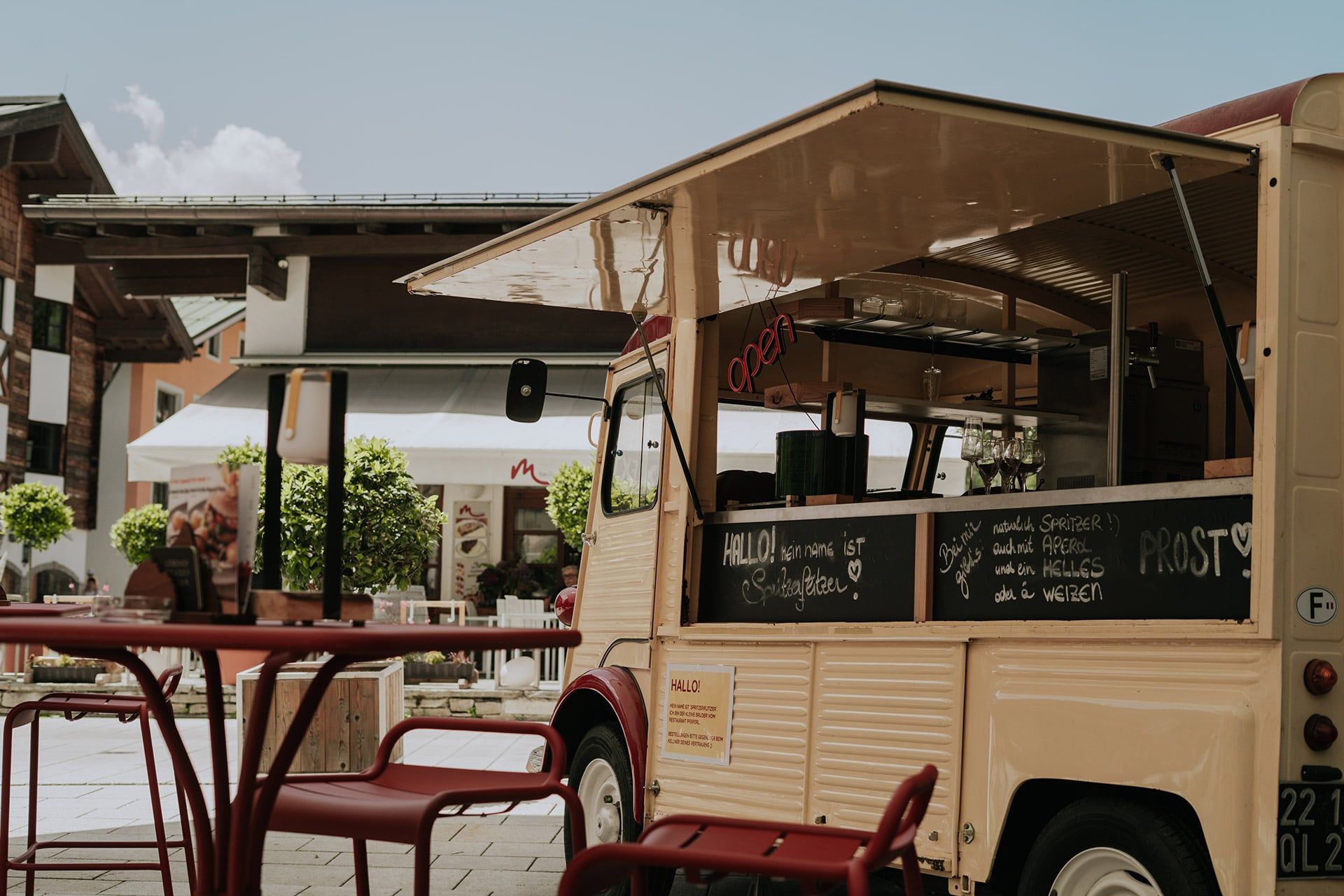 Im Glemmtal steht ein Foodtruck mit freundlichem Angebot und einladenden Tischen.