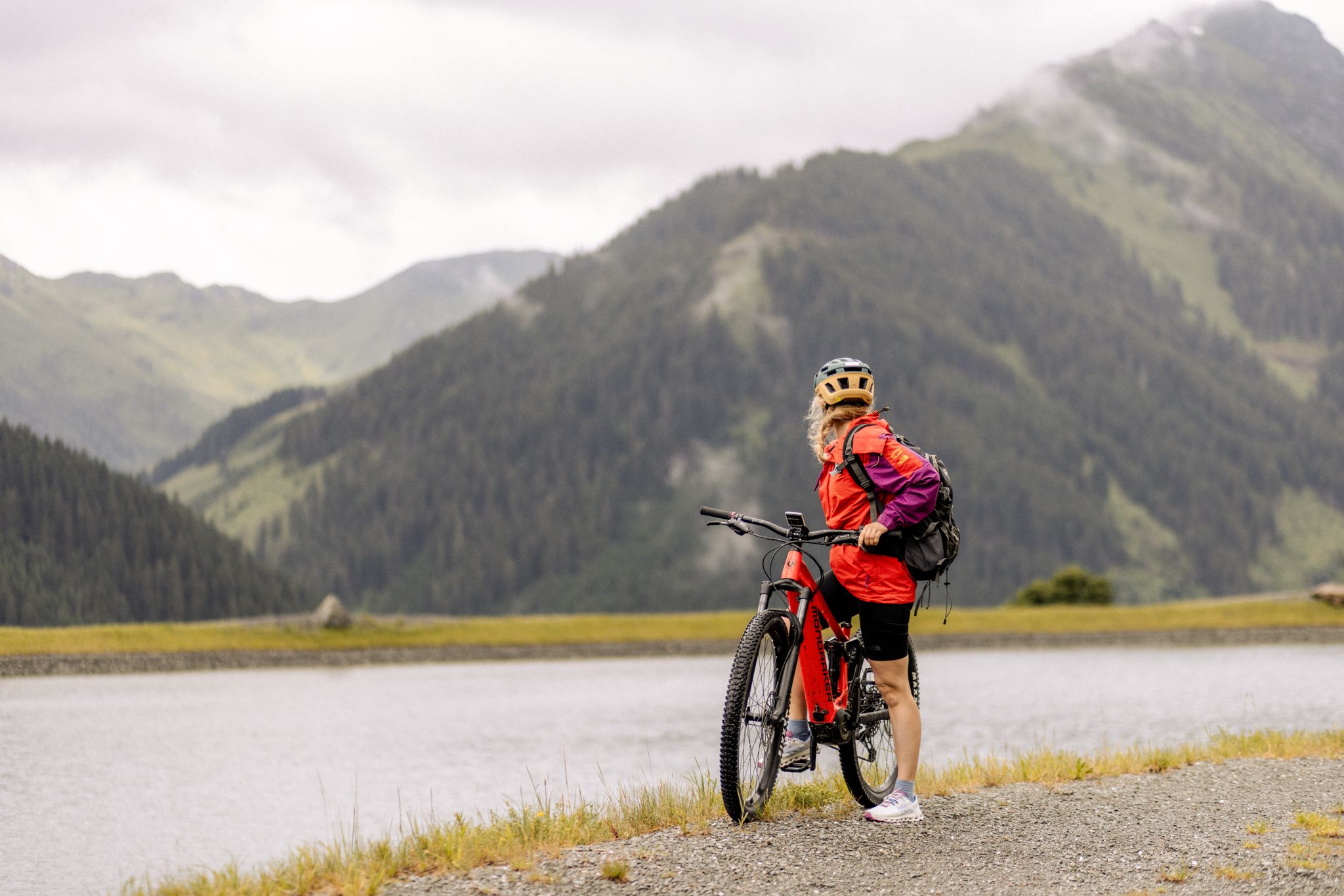 A cyclist at Glemmtalerhof in Hinterglemm admires the mountains and lake.