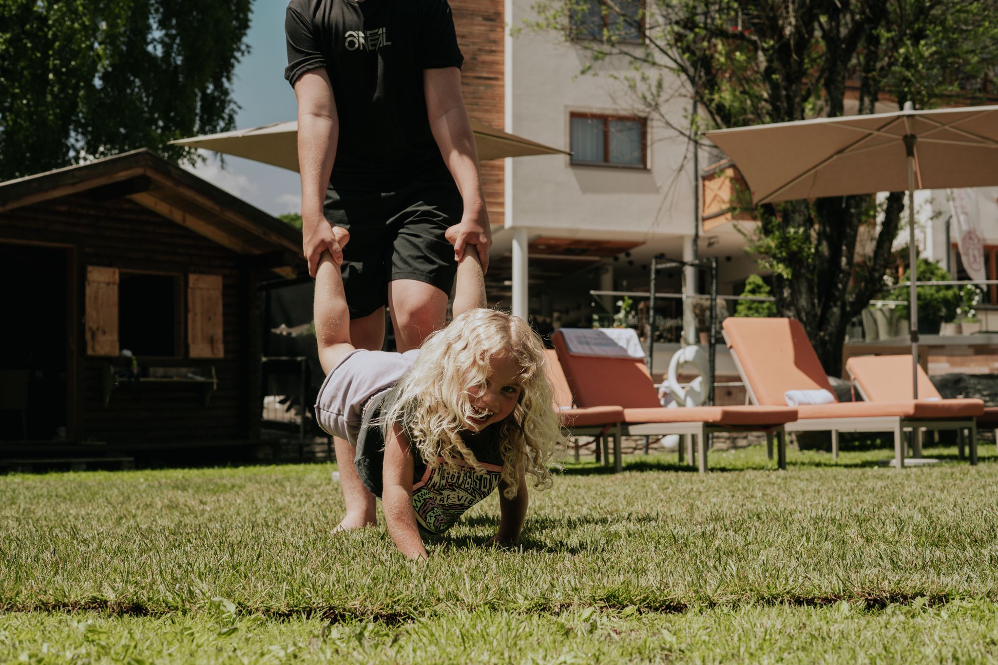 A child plays in Glemmtal while an adult lifts them joyfully.