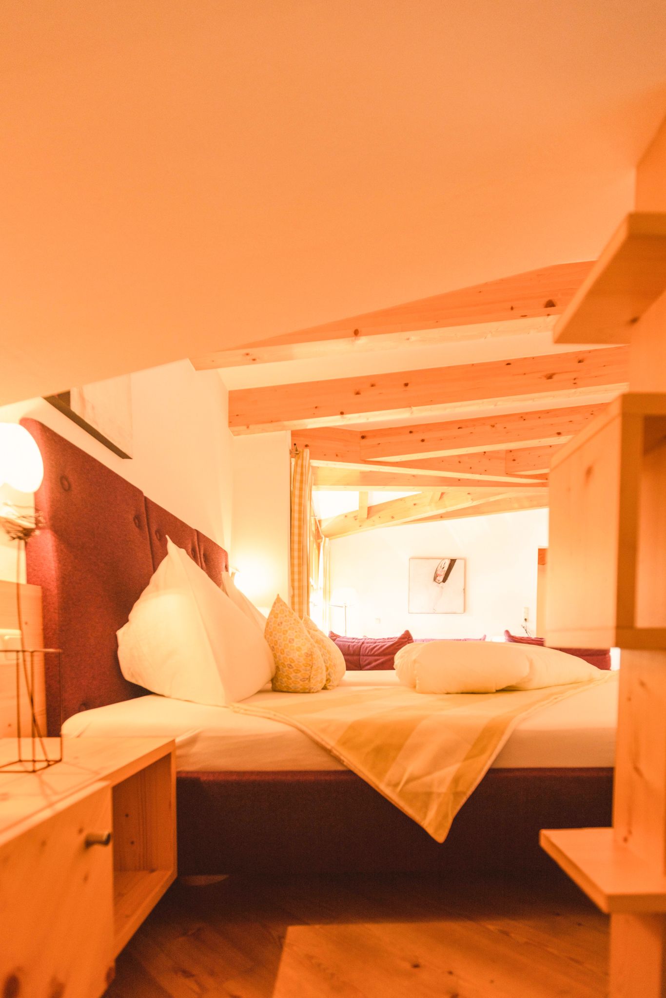 A cozy bedroom in Glemmtalerhof with wooden ceiling and decorative pillows.