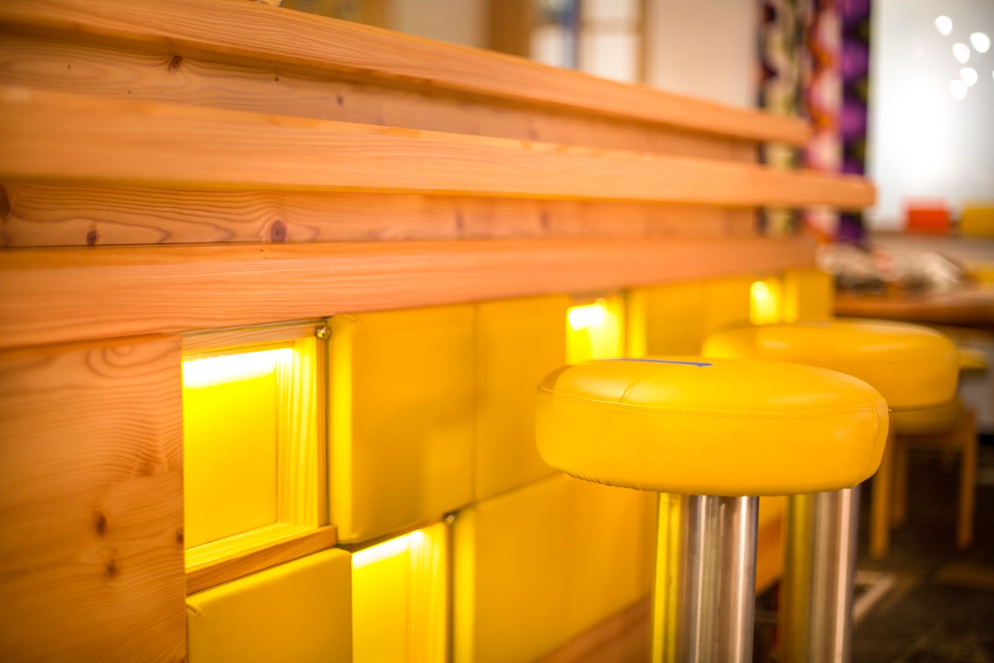 The bar in Glemmtalerhof in Hinterglemm features a modern, warm design with yellow stools.