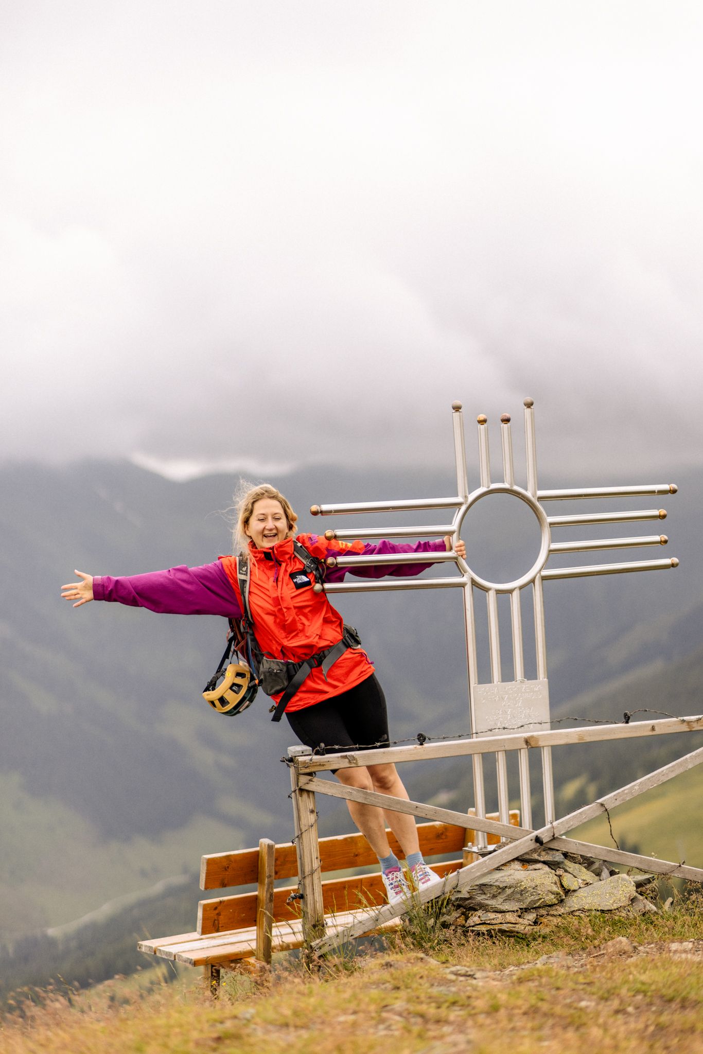 Woman at a peak in Hinterglemm, happily by an alpine symbol.