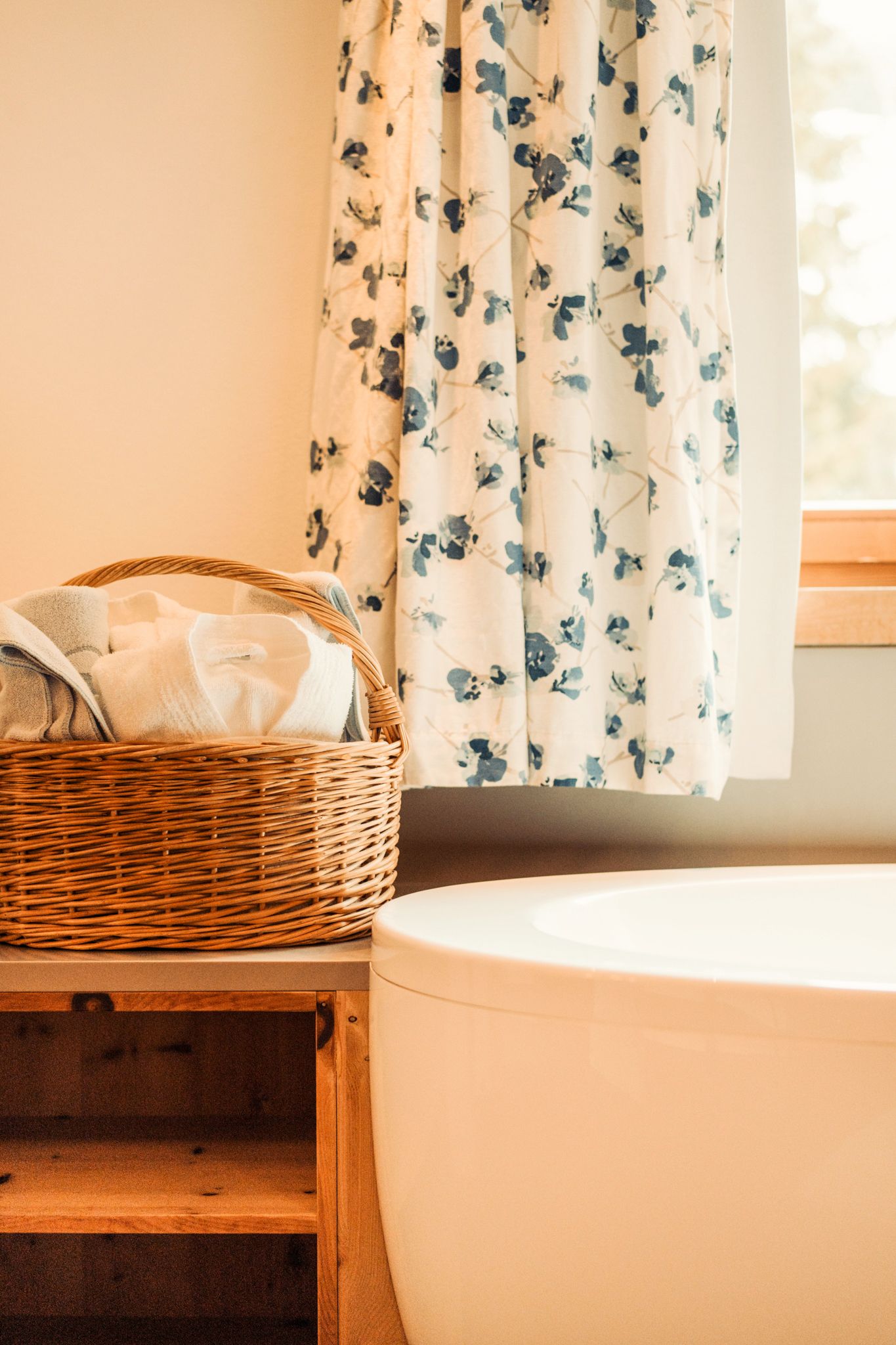 Towels are in a basket next to a stylish bathtub.