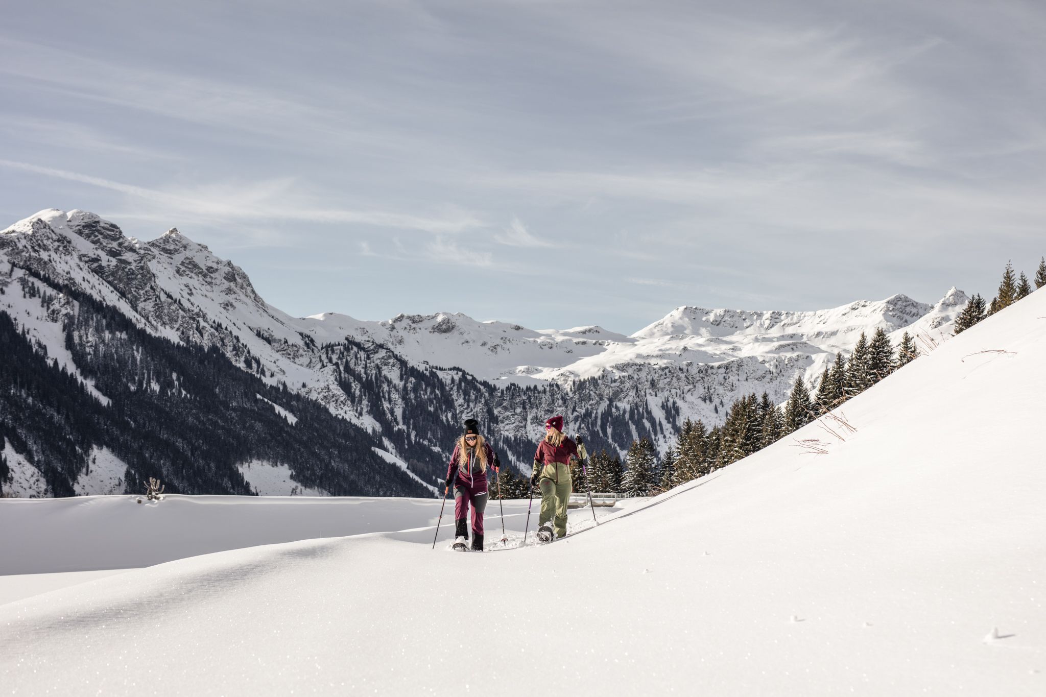 In the Glemmtal, two women hike through the snowy winter forest.