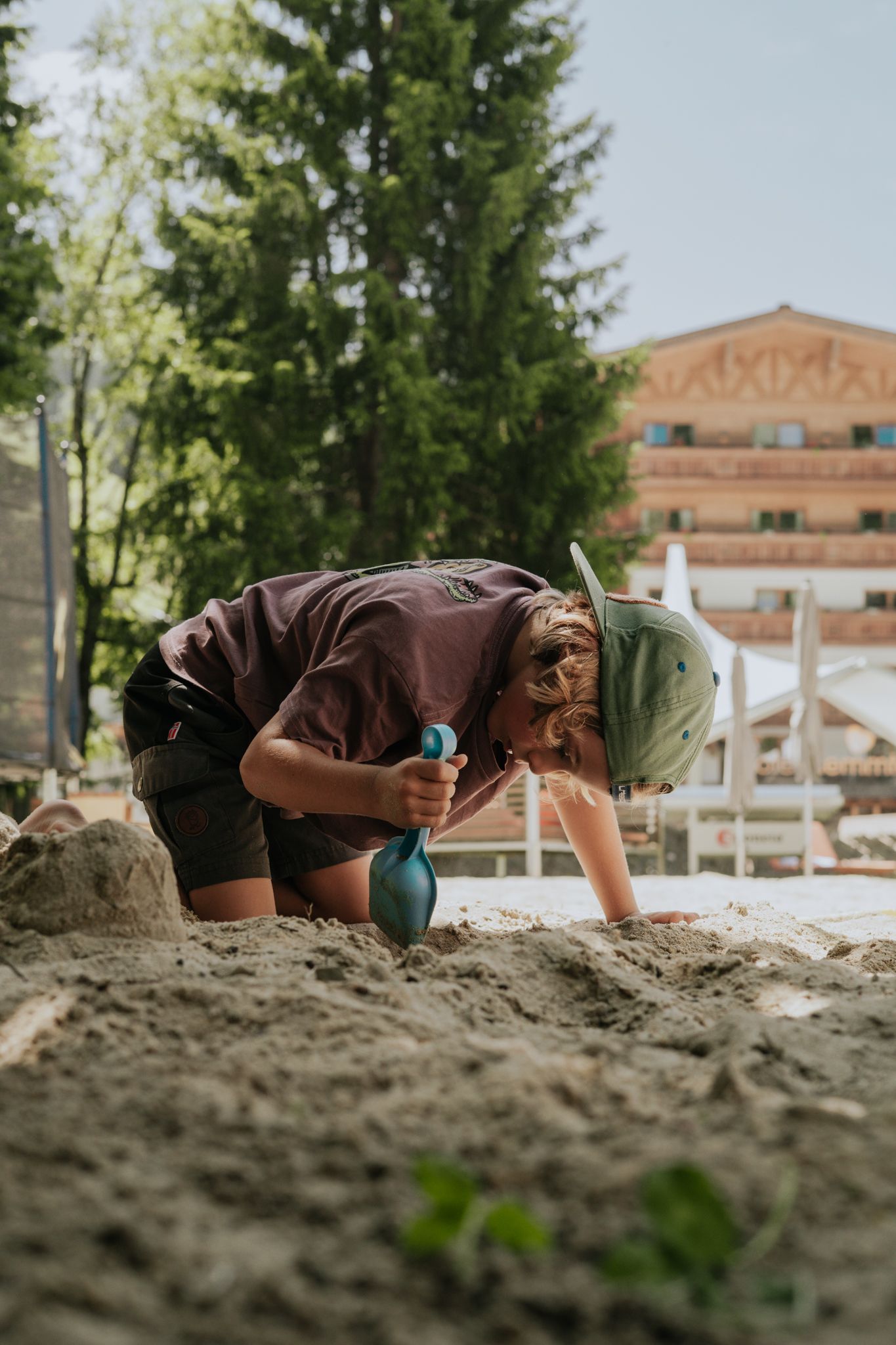 A boy is playing in the sand in front of the Glemmtalerhof in Hinterglemm