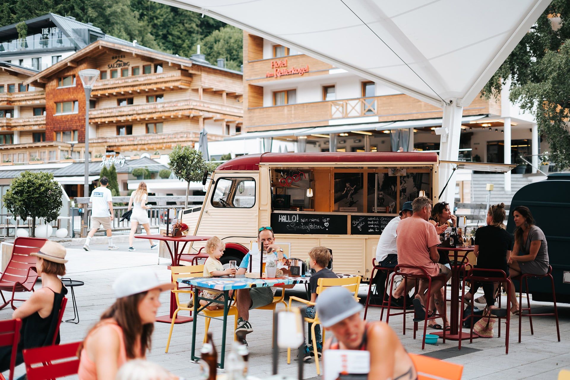 Gäste genießen die Atmosphäre am Glemmtalerhof in Hinterglemm vor einem Food Truck.