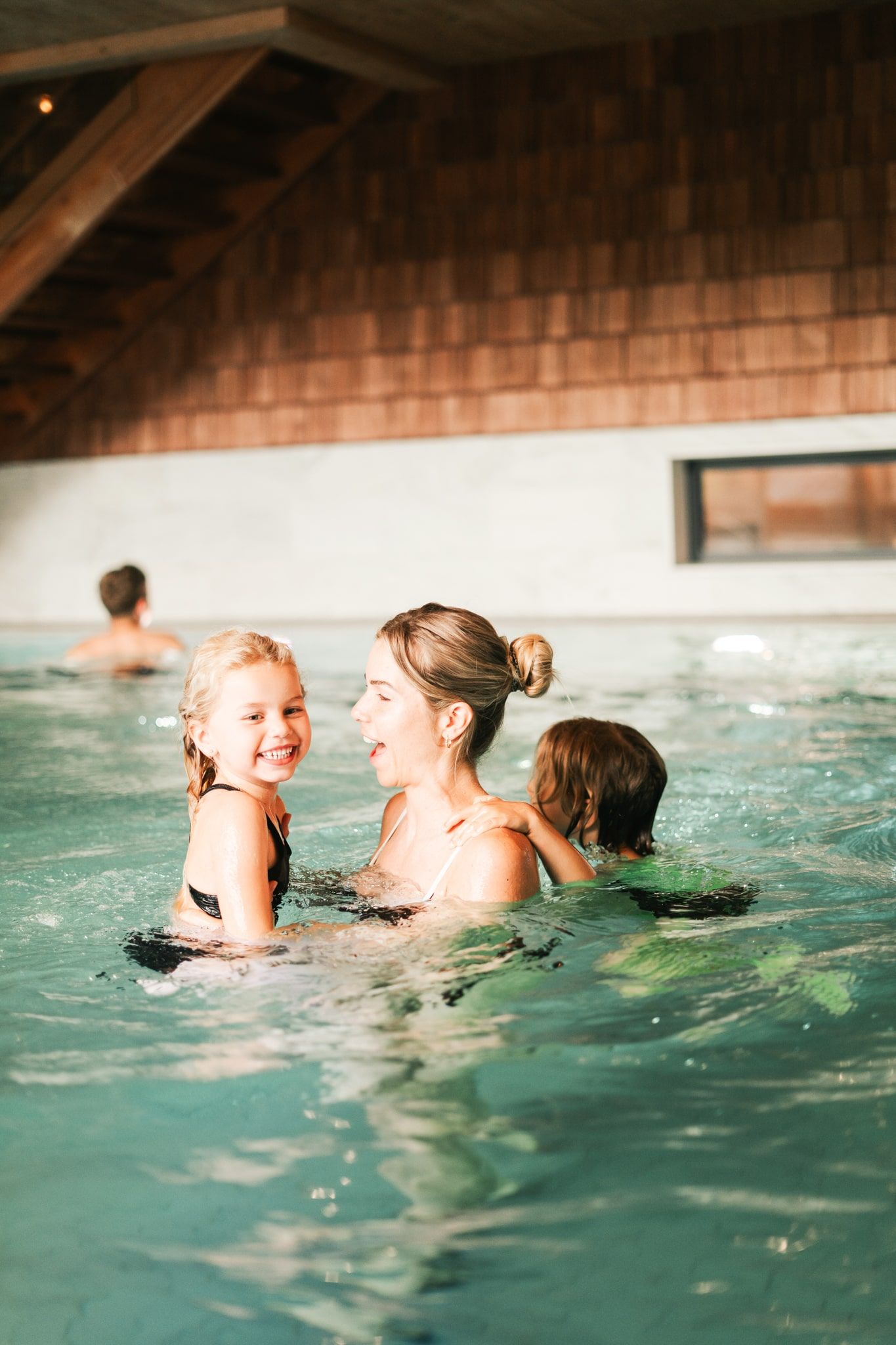 Eine Mutter spielt mit ihren Kindern im Wasser des Glemmtalerhof in Hinterglemm.